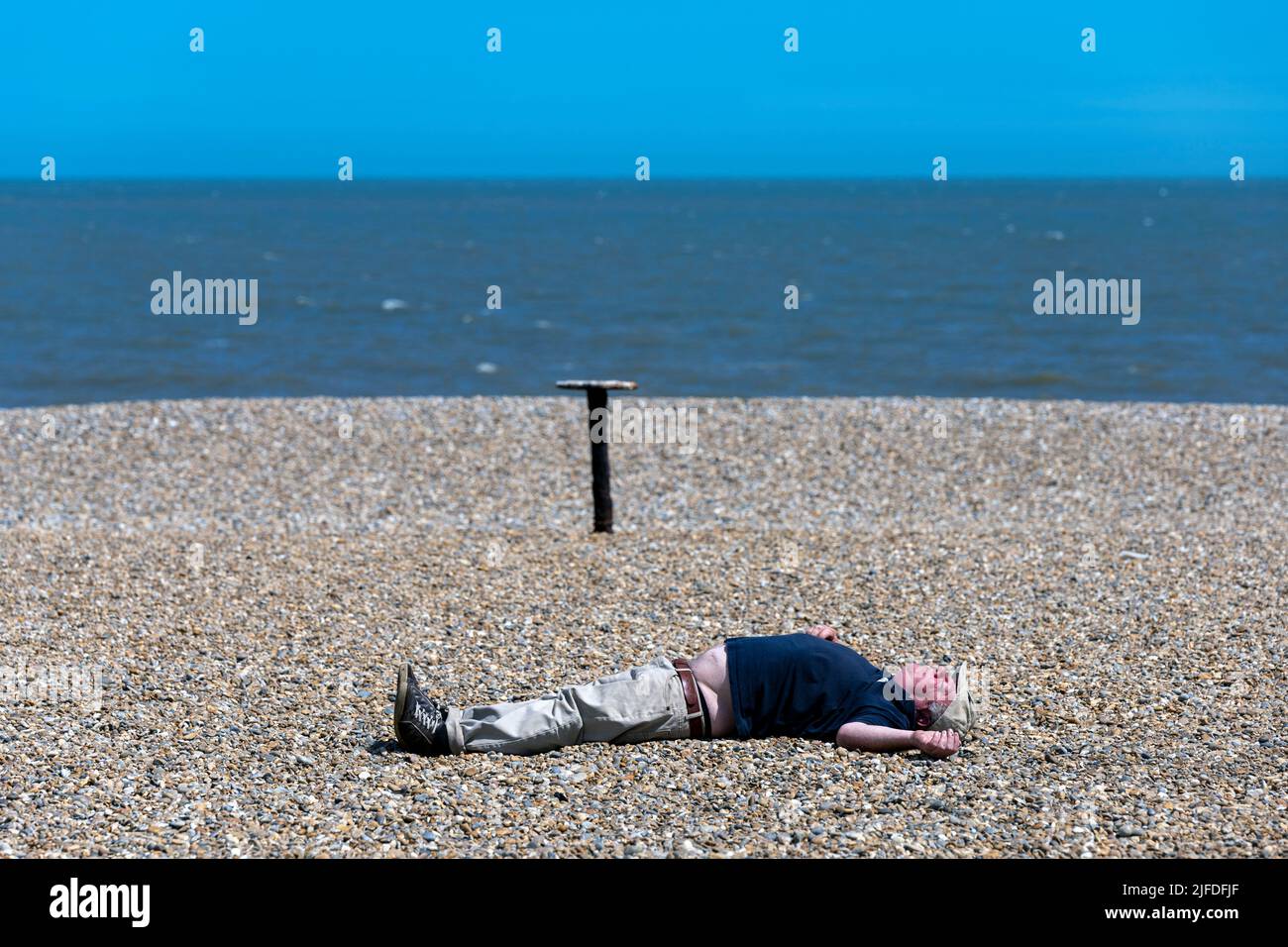 Homme prenant un bain de soleil sur Aldeburgh Suffolk Banque D'Images