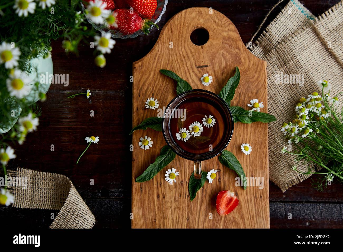 Camomille biologique et thé à la menthe, thé à base de plantes, antioxydant. Fraises fraîches, fleurs de camomille sur table en bois. Thé d'été rustique. Style de vie estival esthétique. La cuisine est délicieuse Banque D'Images