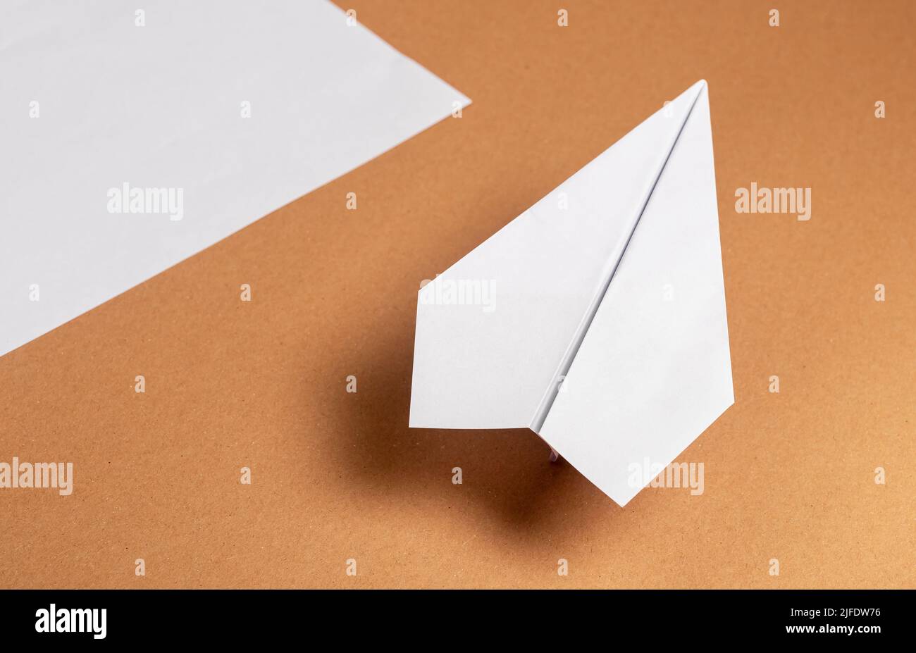 Plan d'origami blanc et feuille de papier sur fond marron avec ombre. Construction volante à la main. Photo de haute qualité Banque D'Images