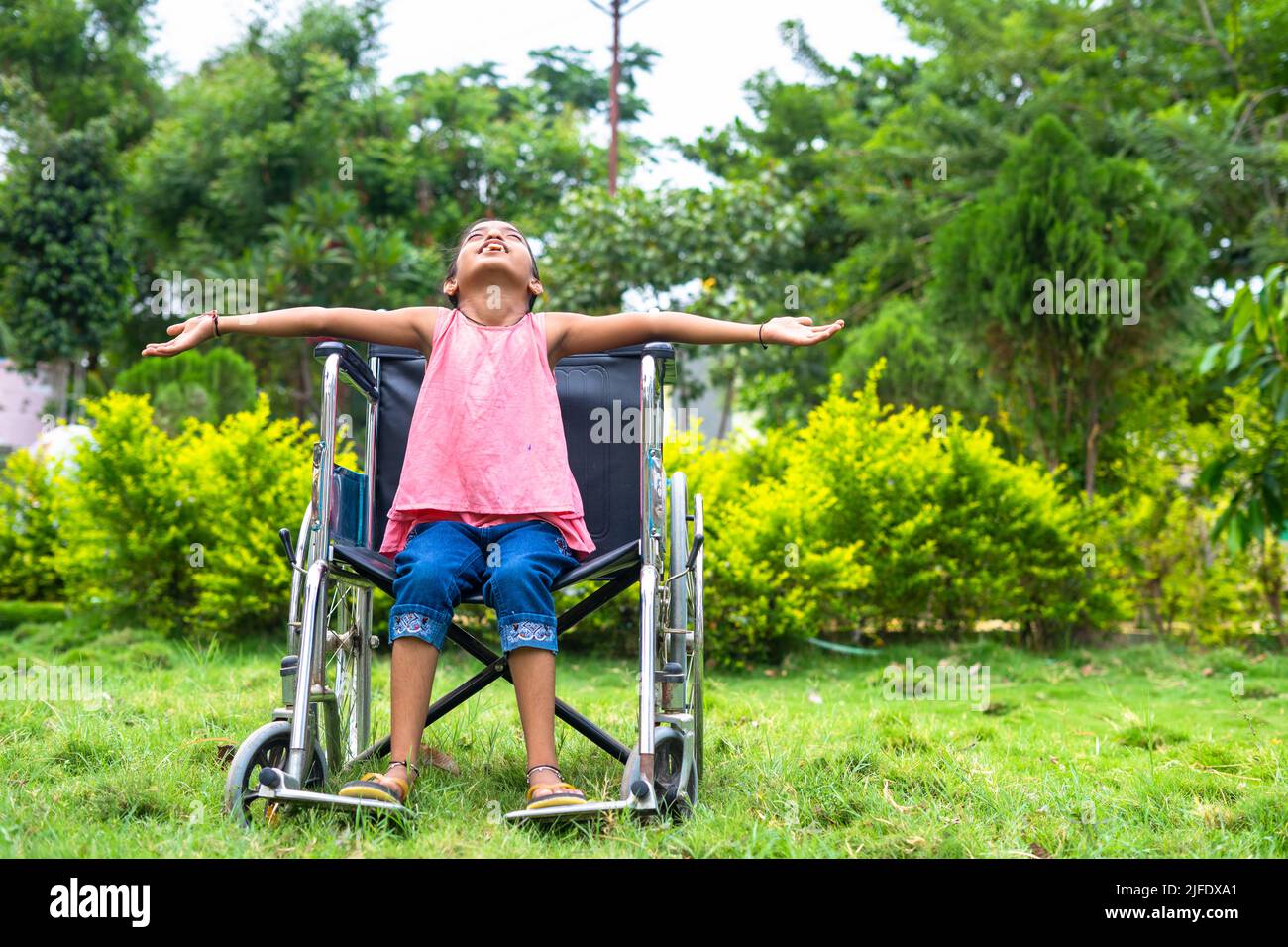 Le concept de liberté, individualité et courage est mis en avant par une fille heureuse qui ressent la nature en étirant les bras en fauteuil roulant dans une maison de soins infirmiers. Banque D'Images