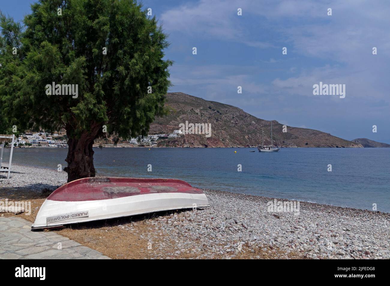 Bateau de pêche retourné sous un arbre tamarisque. Le Marco Polo, scène de plage, village Livadia, île de Tilos, Dodcanese, Grèce Banque D'Images