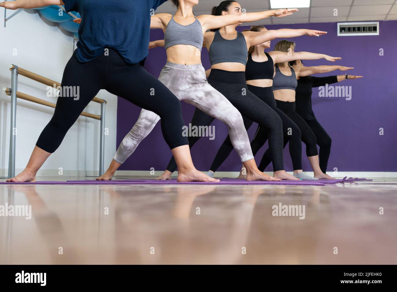 Groupe de femmes pratiquant le guerrier deux posent sur la classe de yoga Banque D'Images