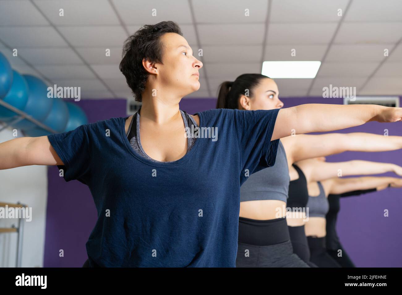 Vue à angle bas d'un groupe de femmes pratiquant deux poses guerriers sur la classe de yoga Banque D'Images