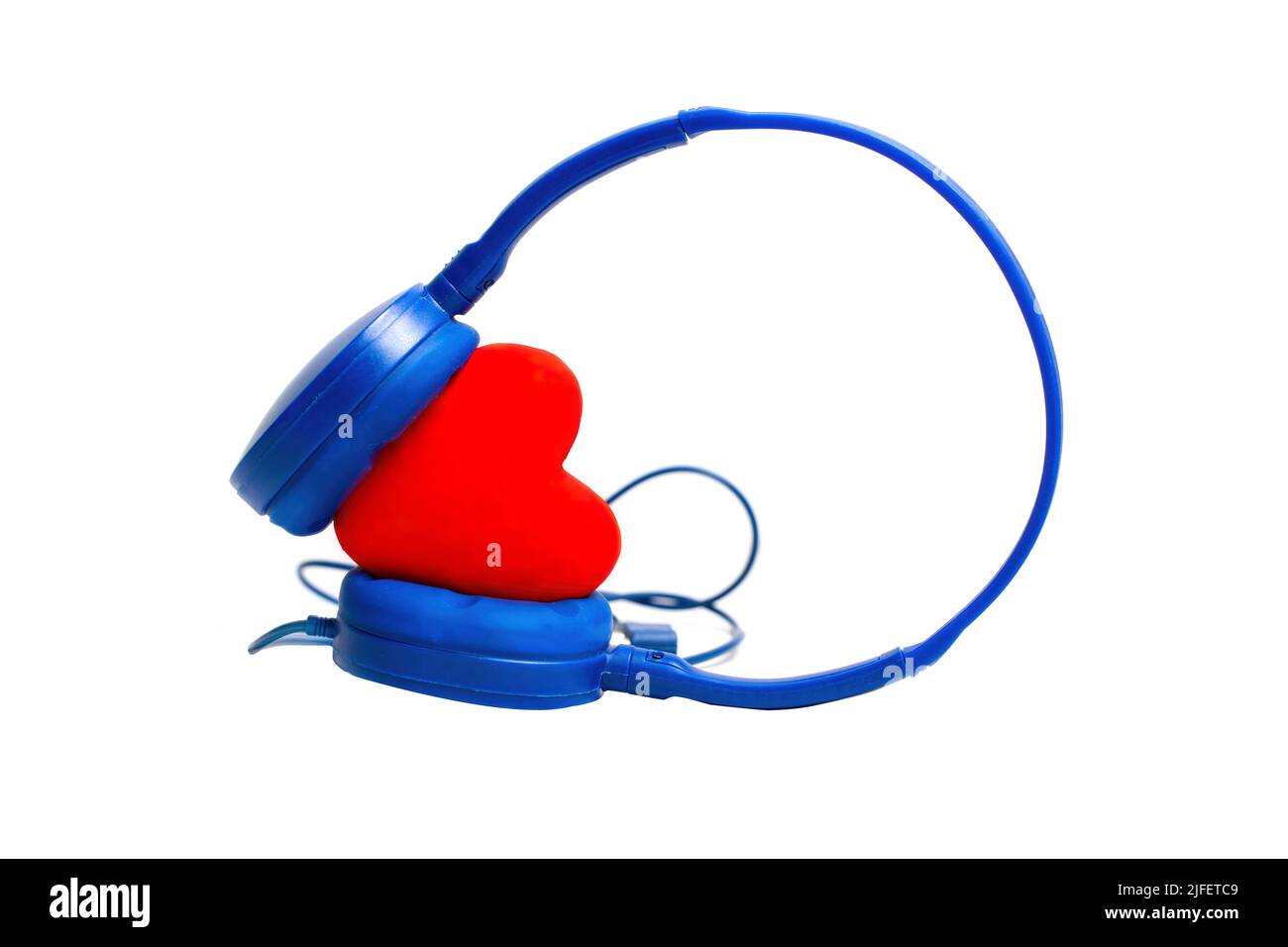 Les écouteurs de voyage avec fil bleu sont placés sur un cœur rouge isolé sur un fond blanc. Banque D'Images