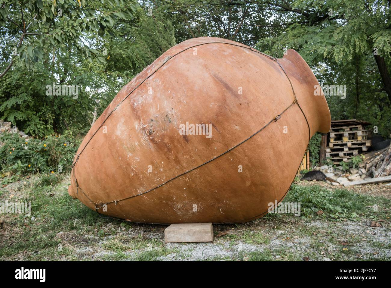 Grand kvevri dans le jardin en face d'un mur de pierre, Géorgie Banque D'Images