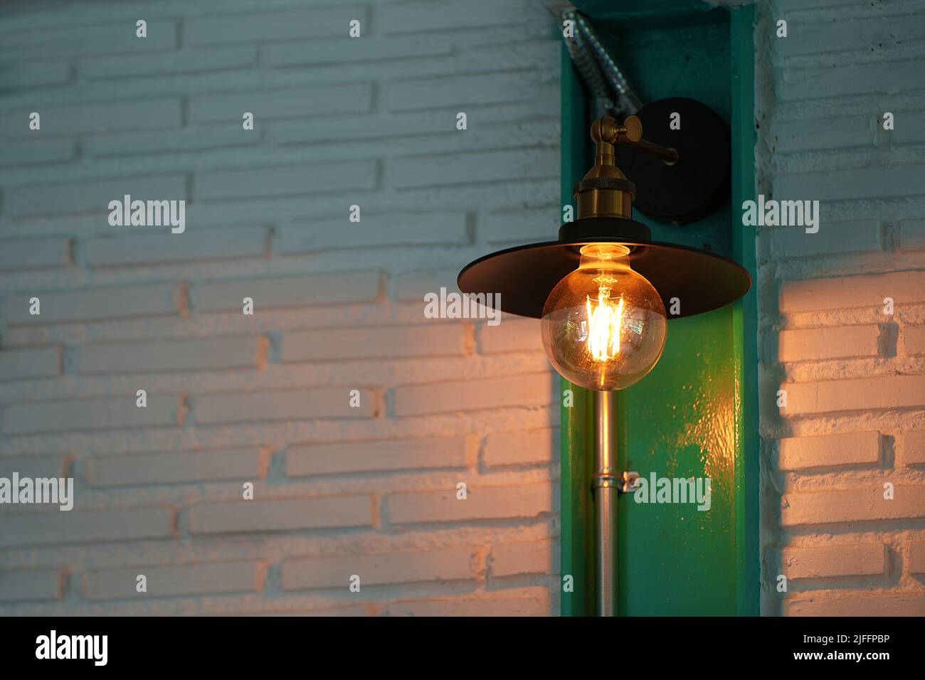 Lampe edison à LED vintage ou ampoule incandescent dans le restaurant ou le café avec paroi ancienne en blocs de tons marron et orange Banque D'Images