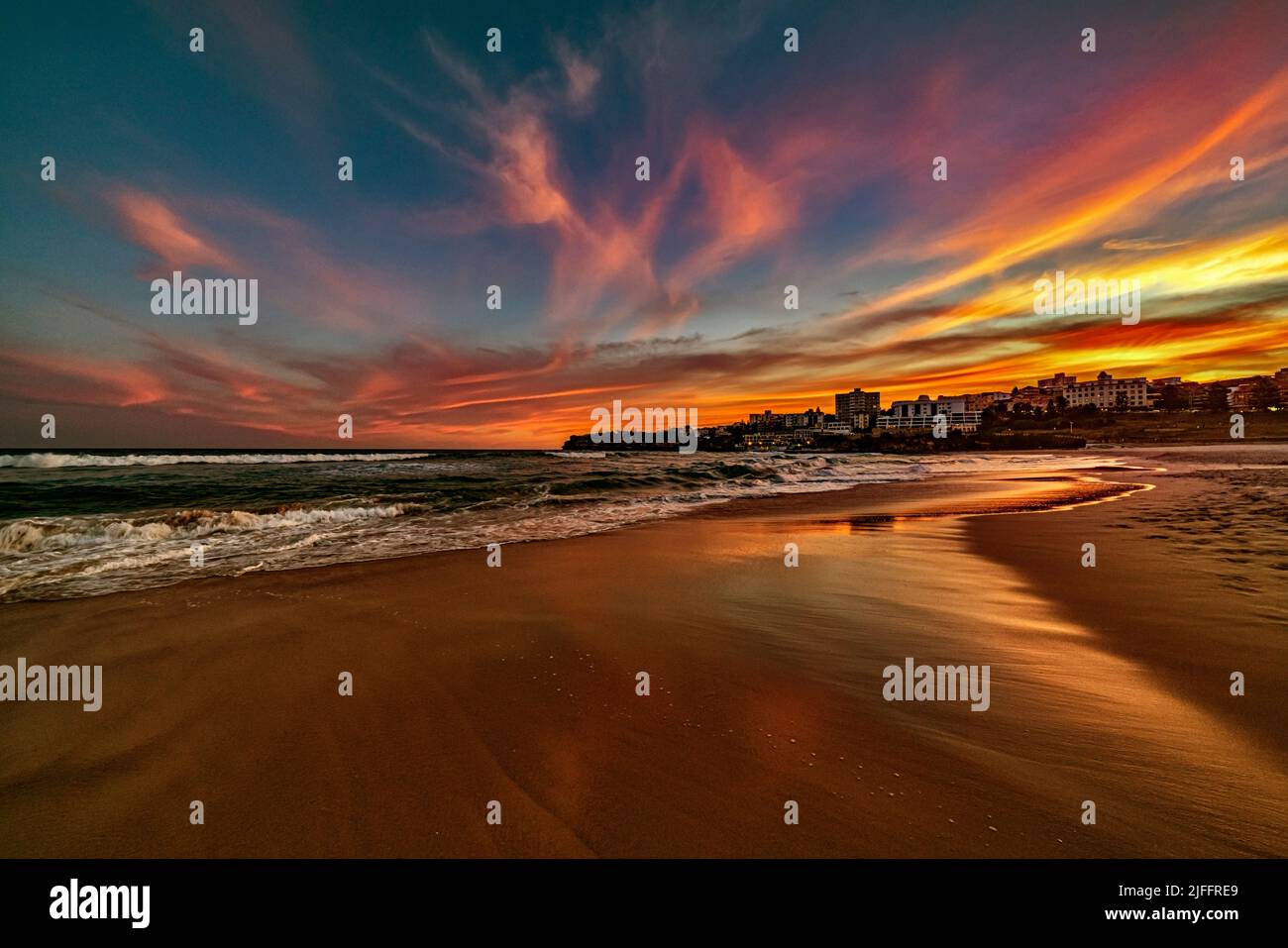 Un ciel magnifique et coloré tandis que le soleil se lève sur la célèbre plage de Bondi Beach à Sydney, en Australie. Regarder vers le sud sur le sable déserté est magique Banque D'Images