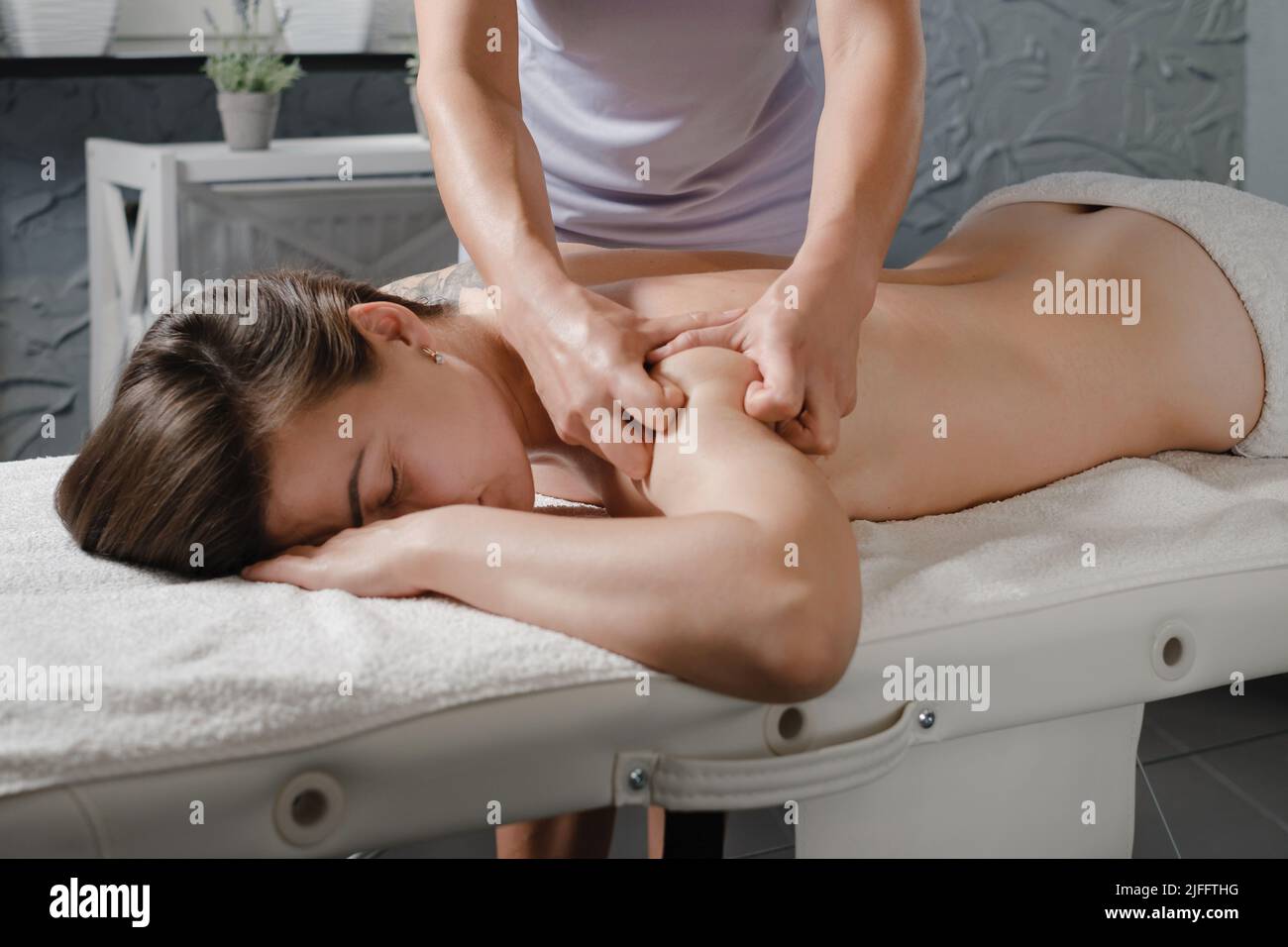 Femme caucasienne ayant un traitement du corps en clinique professionnelle. Massage des épaules à l'huile, spa asiatique et concept de soins de santé. Relaxation et soulagement de la douleur de Banque D'Images