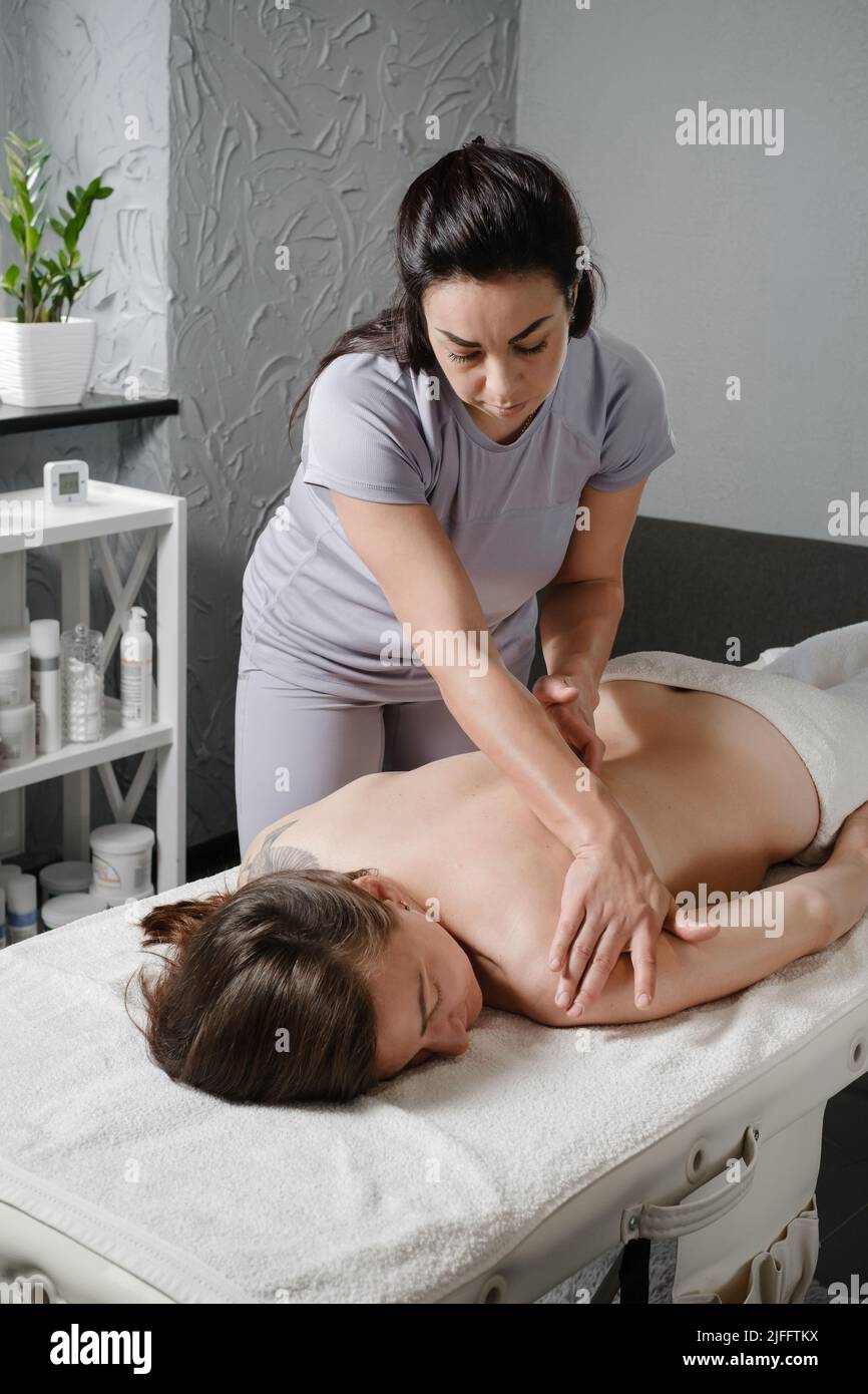 Femme caucasienne ayant un traitement du corps en clinique professionnelle. Massage des épaules à l'huile, spa asiatique et concept de soins de santé. Relaxation et soulagement de la douleur de Banque D'Images