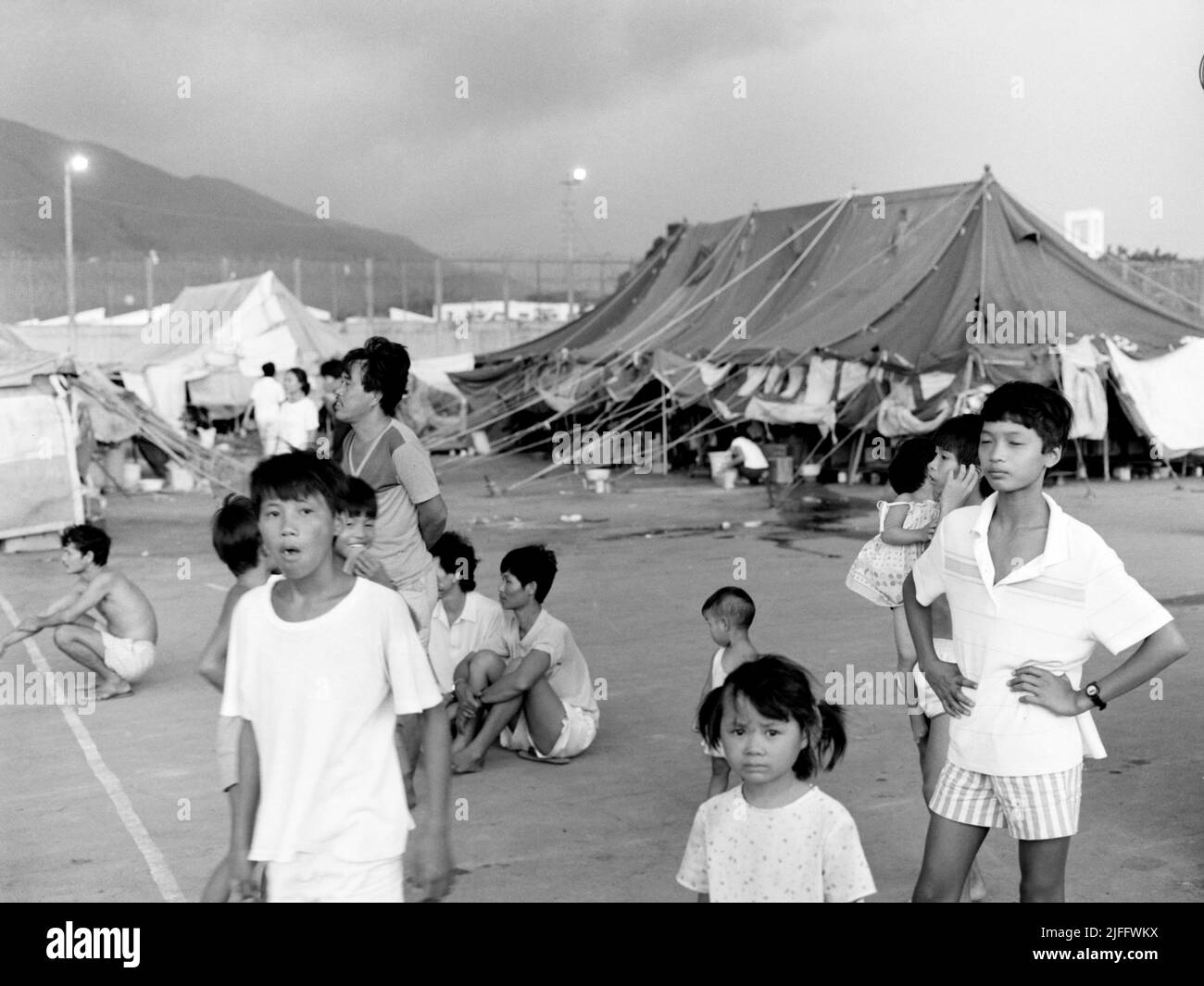 Le Centre de détention vietnamien de Shek Kong, érigé en quelques semaines en 1989 à l'extrémité ouest de la piste militaire de Shek Kong, dans les nouveaux Territoires, à Hong Kong. Des tentes ont été érigées sur la piste et l'herbe de chaque côté, entourée d'une clôture en tôle, surmontée d'un fil barbelé. Des dizaines de milliers de demandeurs d’asile vietnamiens ont traversé le camp au cours des années de son opération photo prise en décembre 1990. Banque D'Images