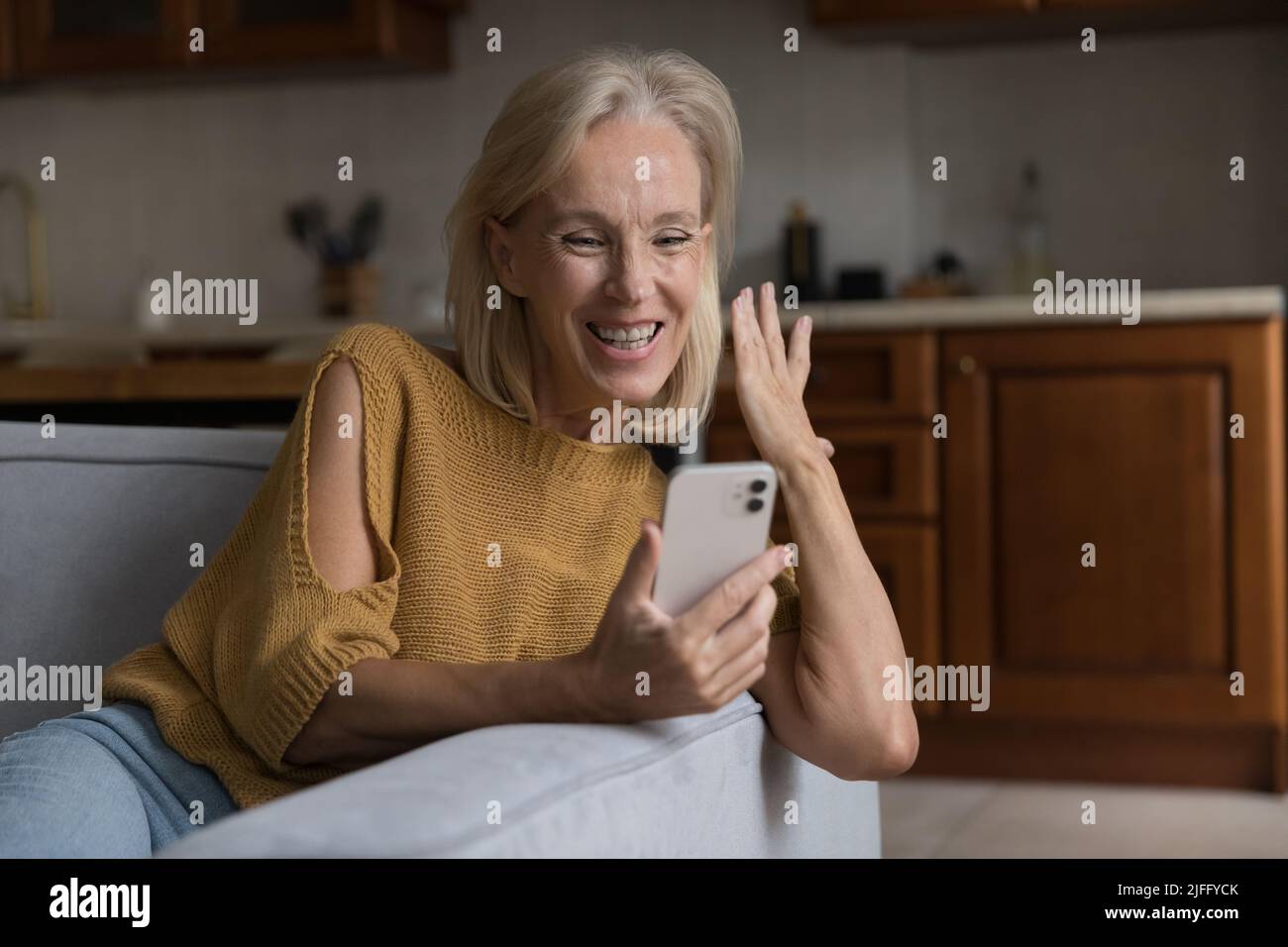 Bonne femme âgée a lu le message avec de grandes nouvelles sur le téléphone portable Banque D'Images