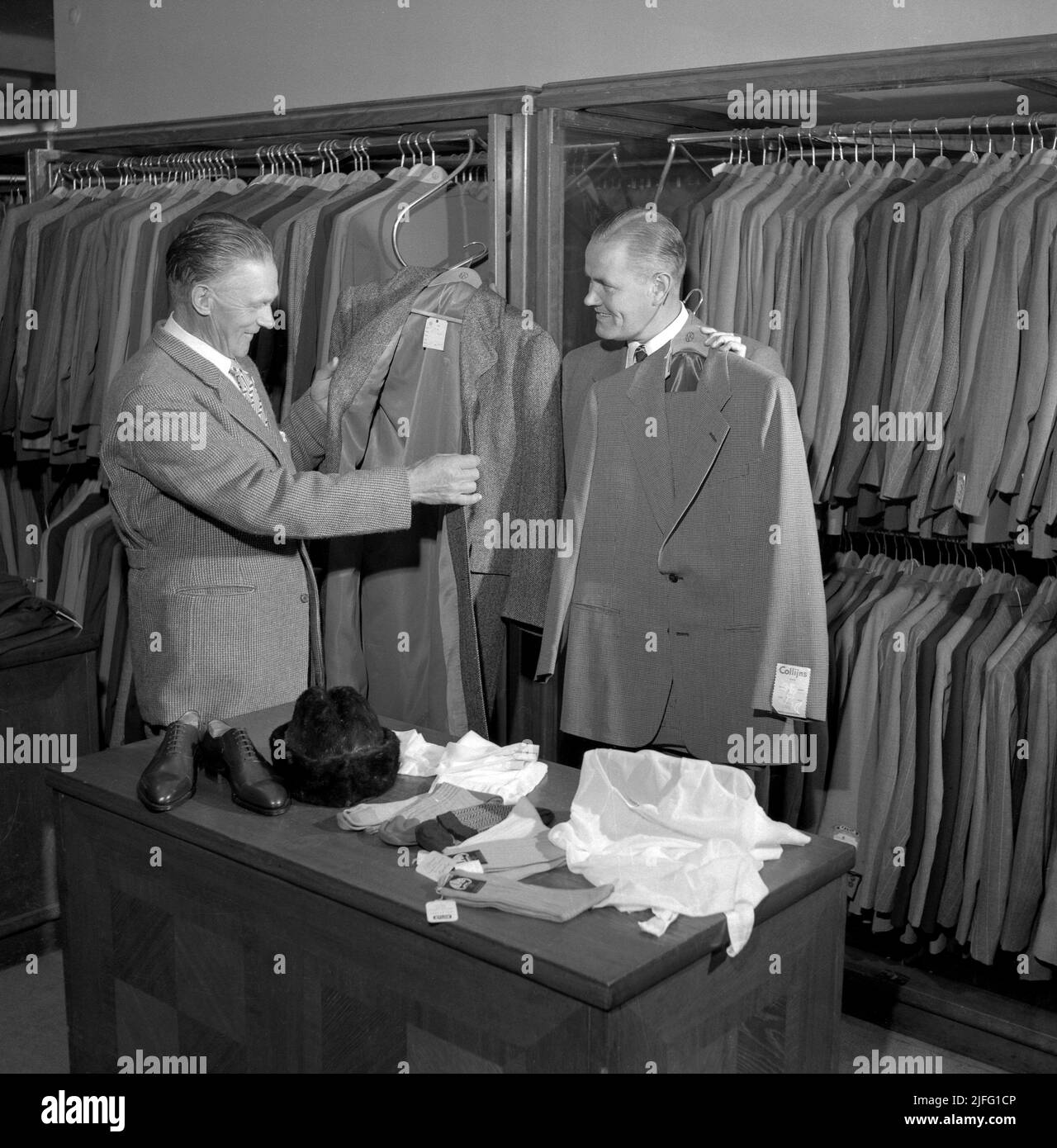 Acheter des vêtements pour hommes en 1950s. Un homme est servi par le vendeur masculin avec les vestes et les costumes disponibles dans le magasin Collljins vêtements pour hommes à Stockholm 1952. Banque D'Images