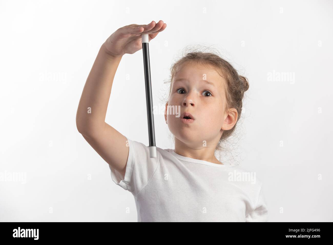 Fille magicienne avec une baguette magique dans ses mains - jeune magicienne exécutant avec une baguette magique - sur fond blanc Banque D'Images