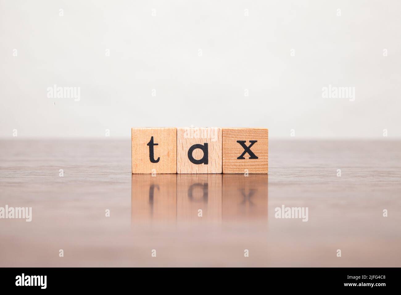 taxe. caractère taxe. Écrit en minuscules sur un bloc de bois. Écrit sur trois blocs empilés sur une table en bois. Banque D'Images