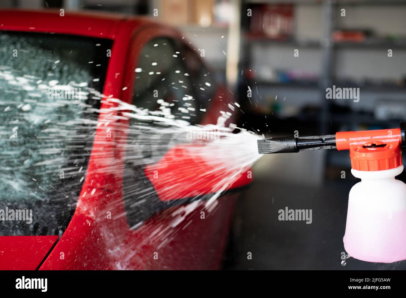 Nettoyage du véhicule rouge avec un pistolet à mousse sous pression Banque D'Images