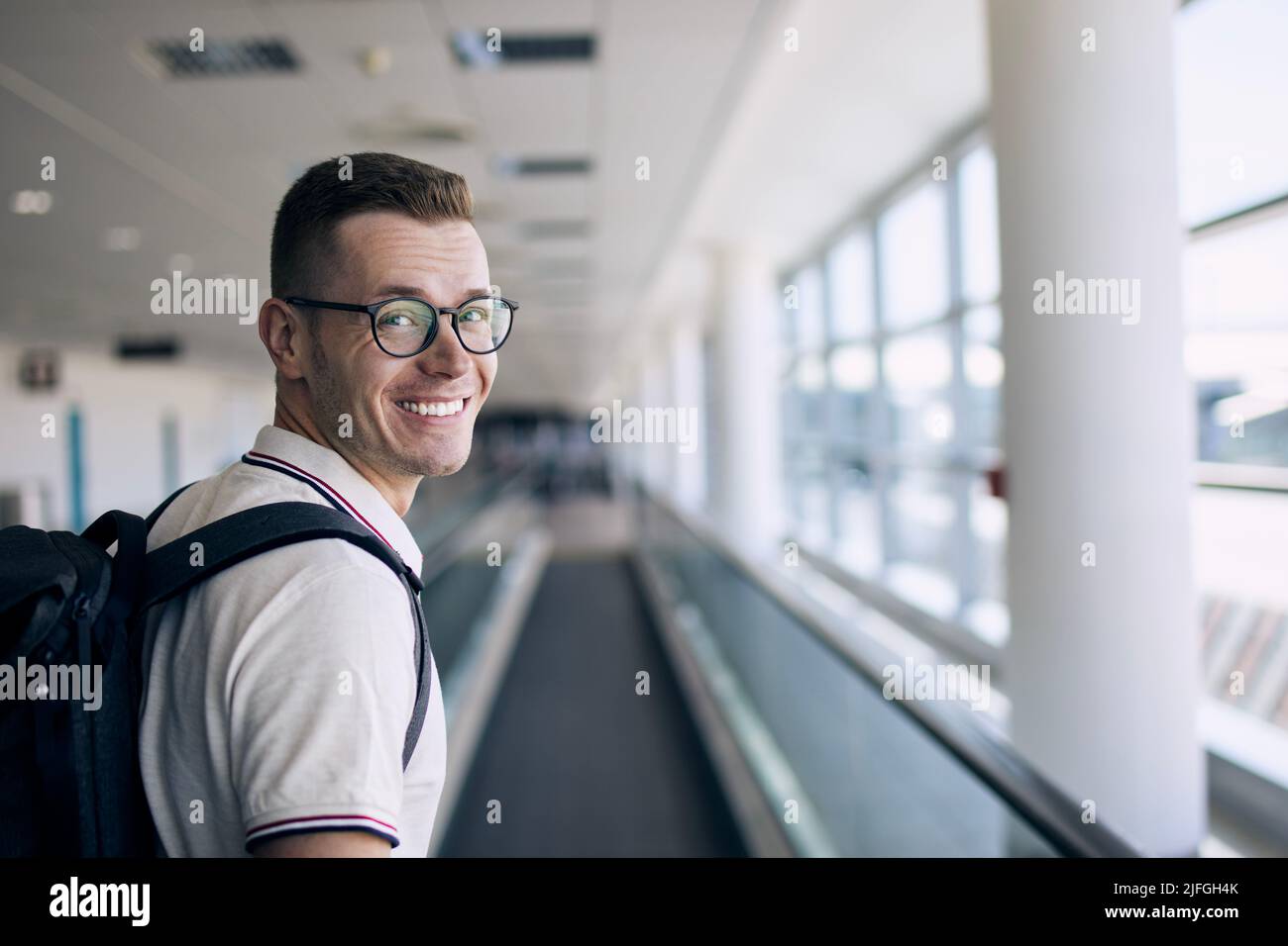 Portrait du voyageur souriant à l'aéroport. Homme heureux regardant l'appareil photo avant son voyage en avion. Banque D'Images