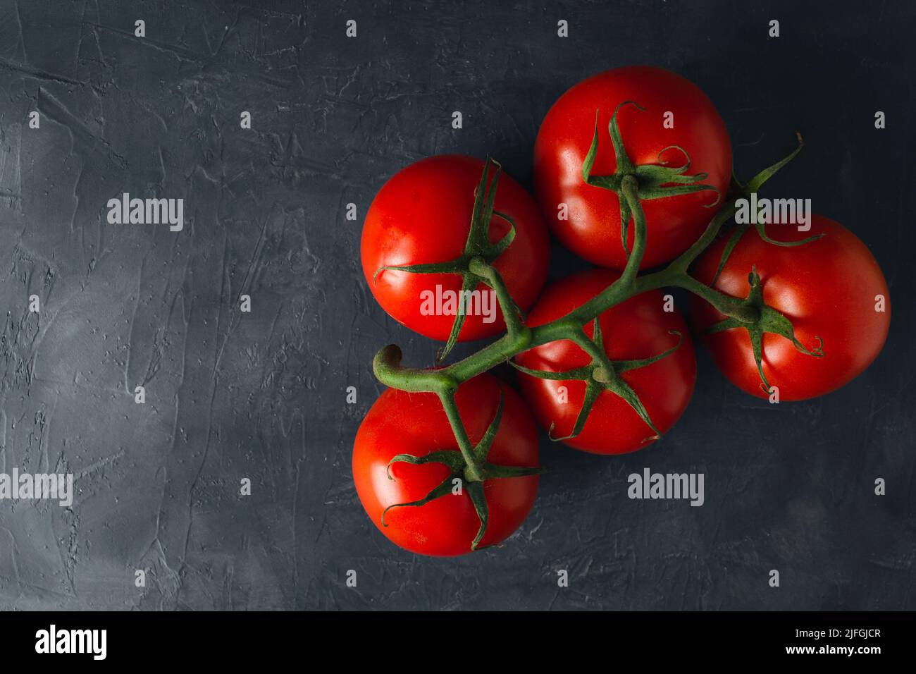 Vue de dessus des tomates mûres rouges sur fond sombre. Tomates fraîches scène sombre avec espace de copie. Banque D'Images