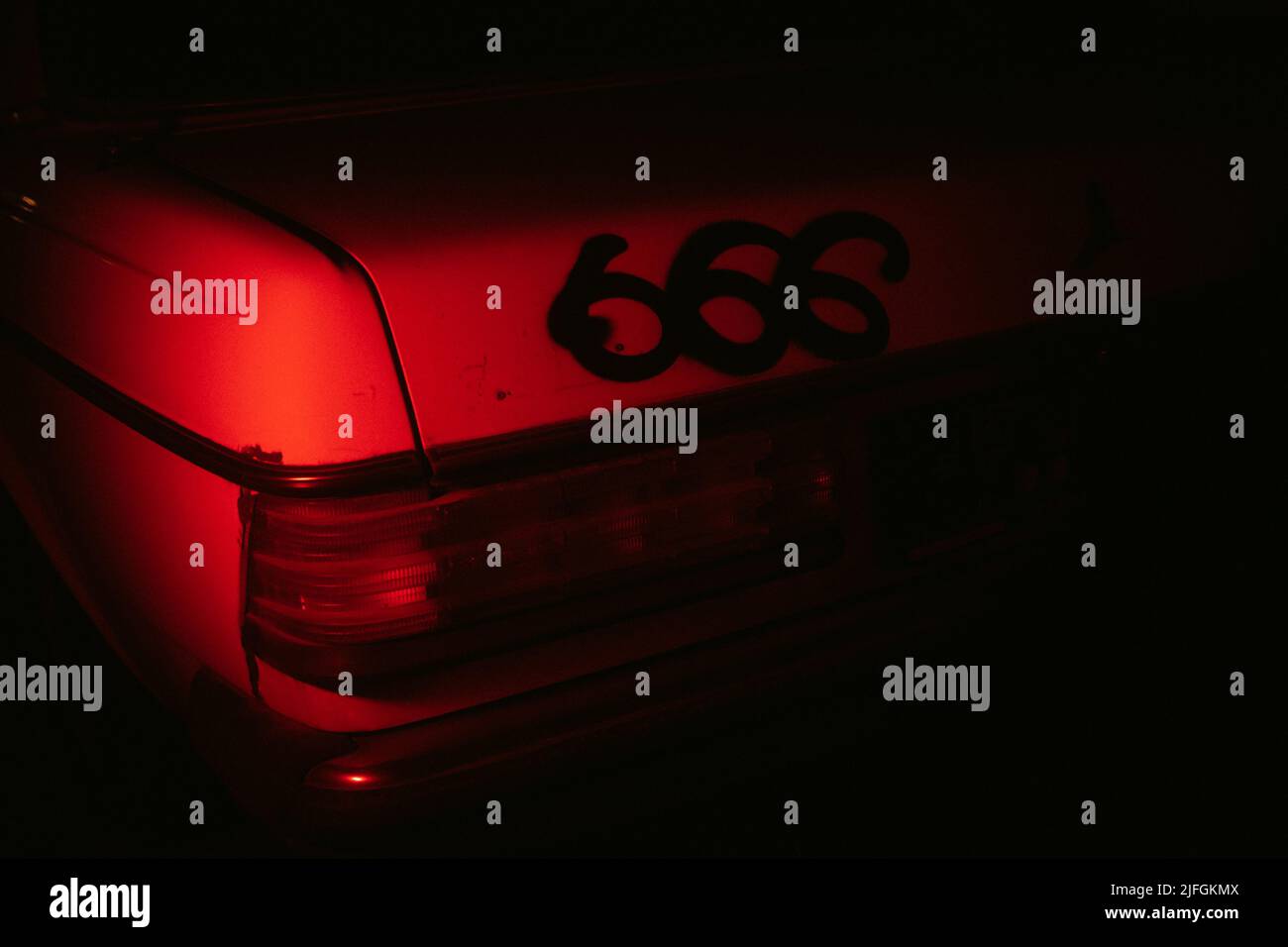 Une photo cinématographique rouge d'une voiture d'époque avec 666 pulvérisé sur le coffre. Banque D'Images