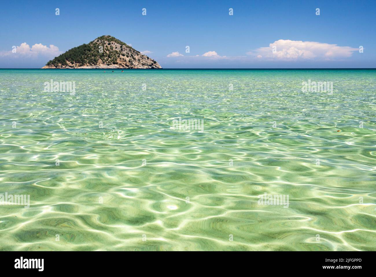 Surface d'eau de mer peu profonde avec réflexion de lumière, petite île en arrière-plan Banque D'Images