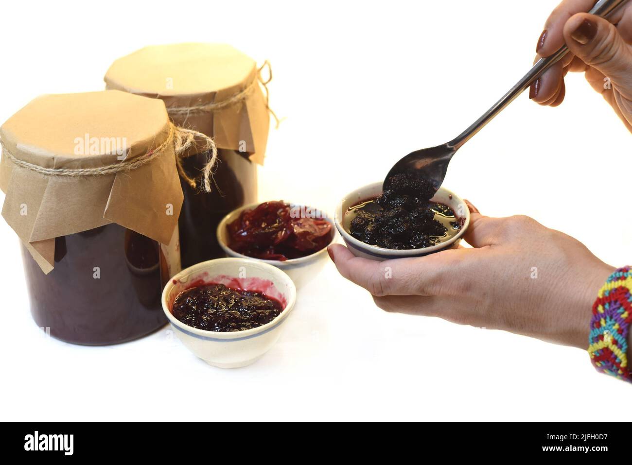 Une main servant de la confiture de mûres maison dans de petits bols en pots Banque D'Images