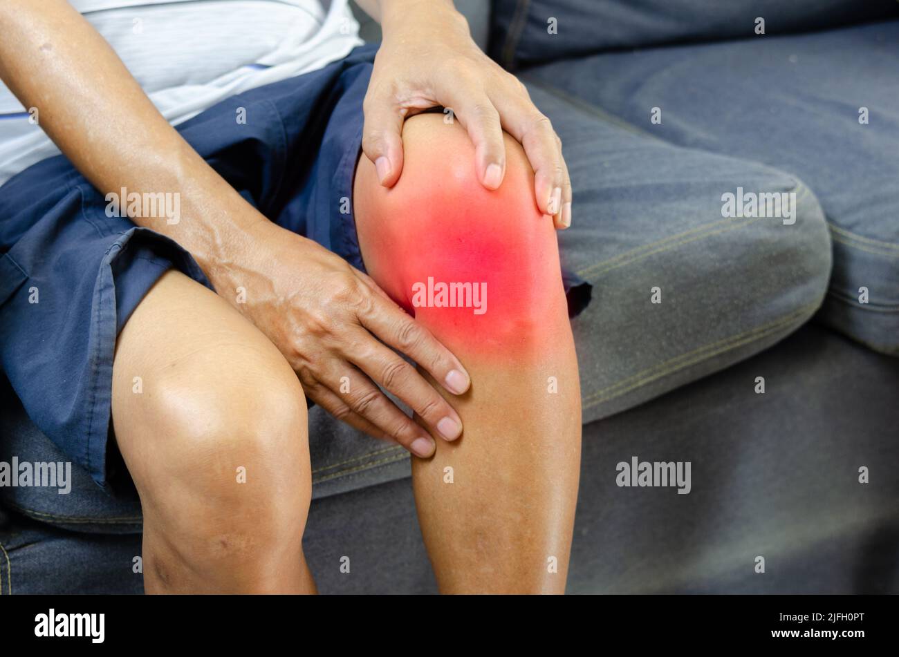 Blessure ou douleur au genou d'un homme âgé sur le canapé. Banque D'Images