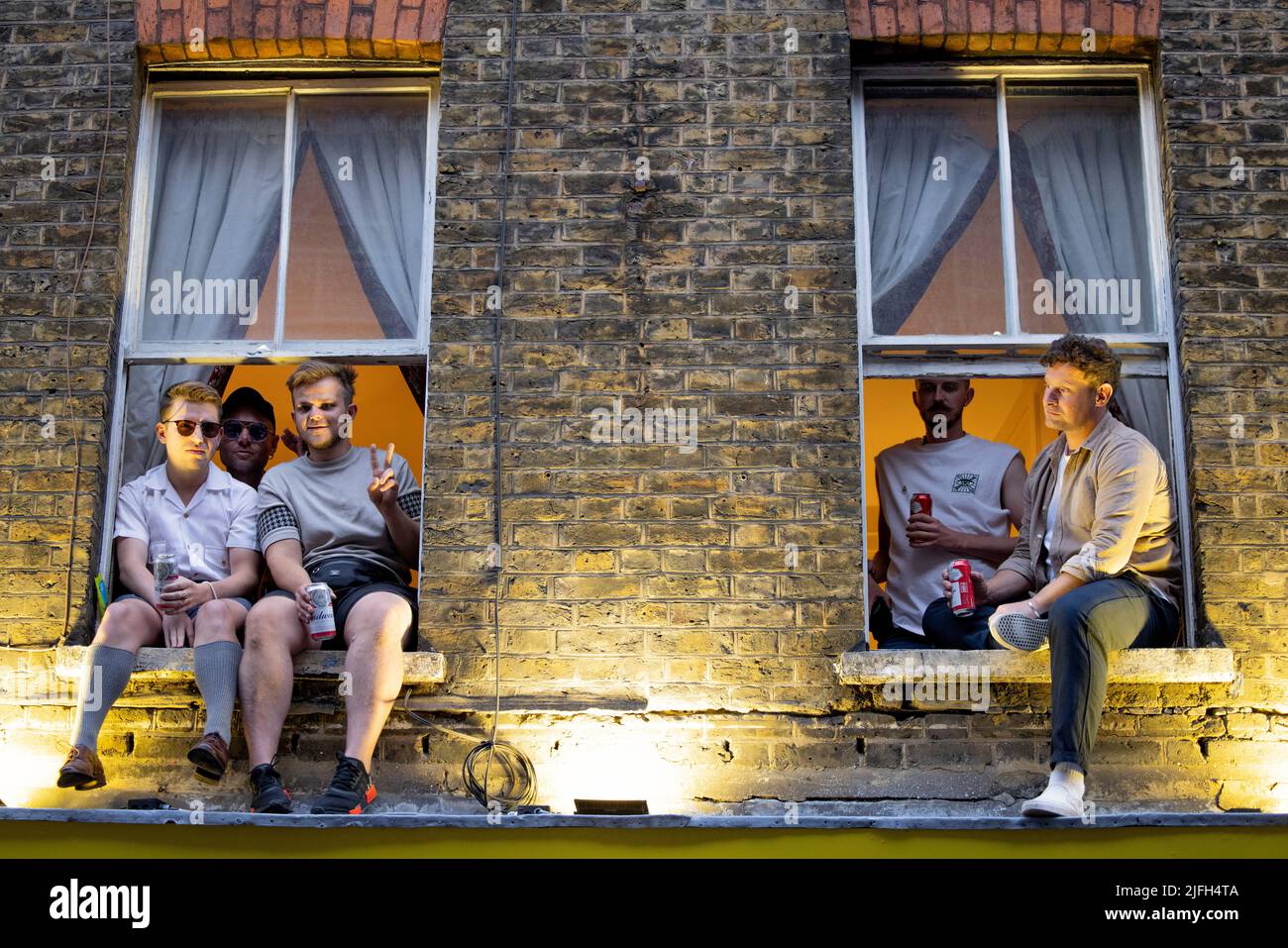 Les résidents de Soho sont vus assis sur leurs fenêtres pour profiter de la vibe de partie à Soho. Le 50th anniversaire de la célébration de la fierté de Londres se poursuit à Soho, dans le centre de Londres, après la fin du défilé de la fierté à Whitehall dans l'après-midi. Banque D'Images