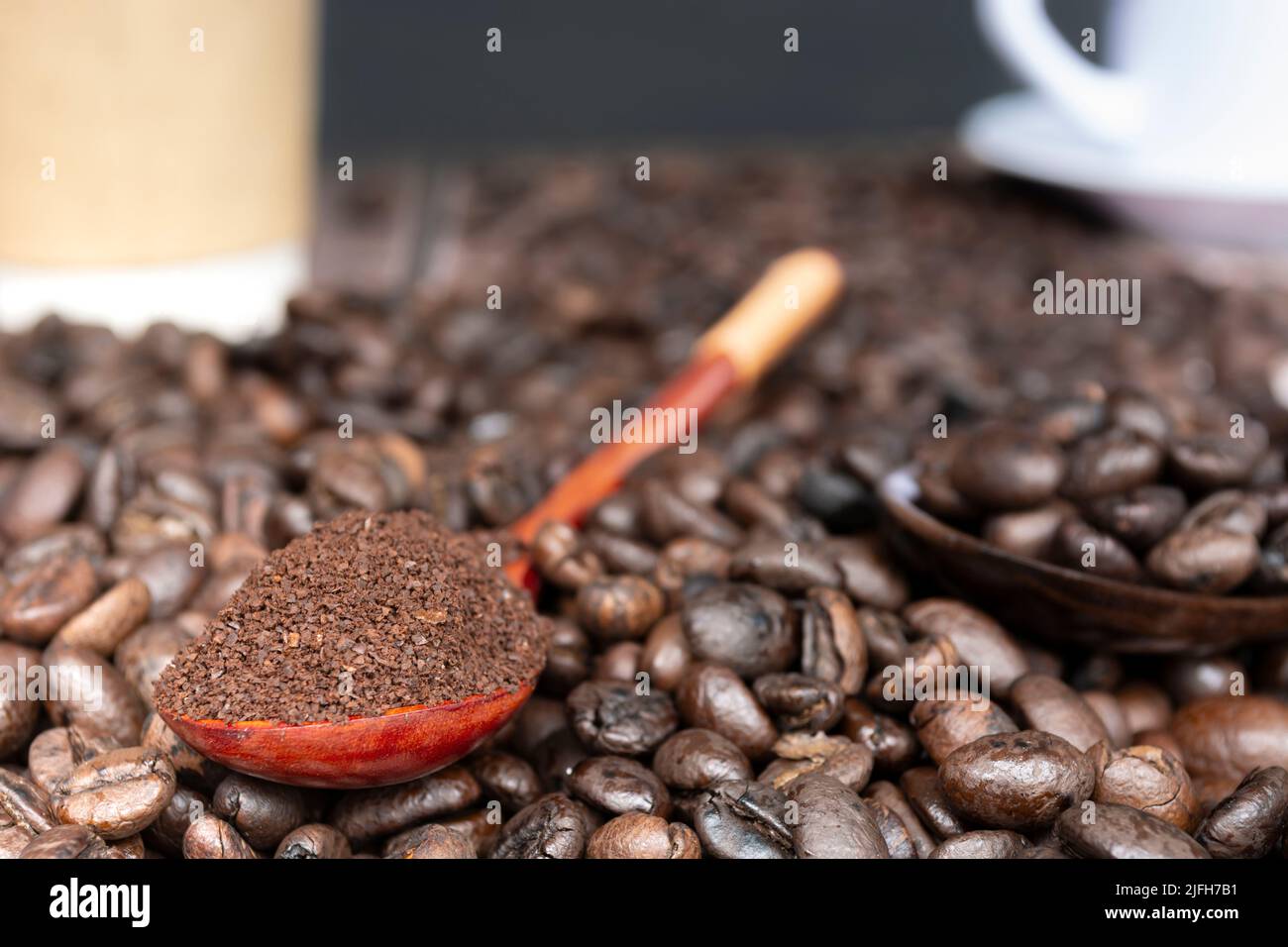 Grains de café torréfiés et café en poudre ou café moulu dans une cuillère en bois isolée sur fond sombre et flou. Banque D'Images