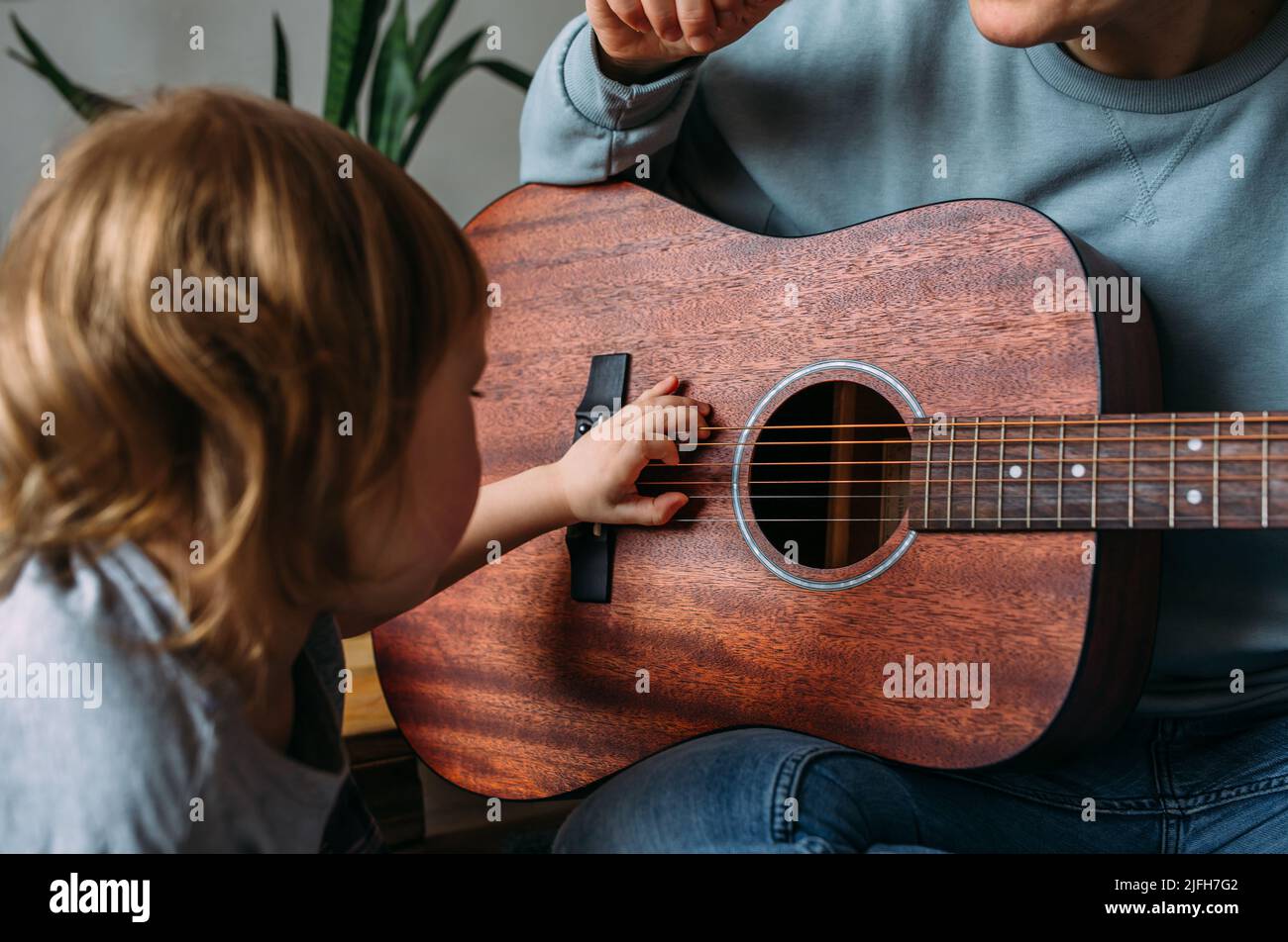 Une petite fille joue de la guitare avec sa mère sur le sol à la maison Banque D'Images