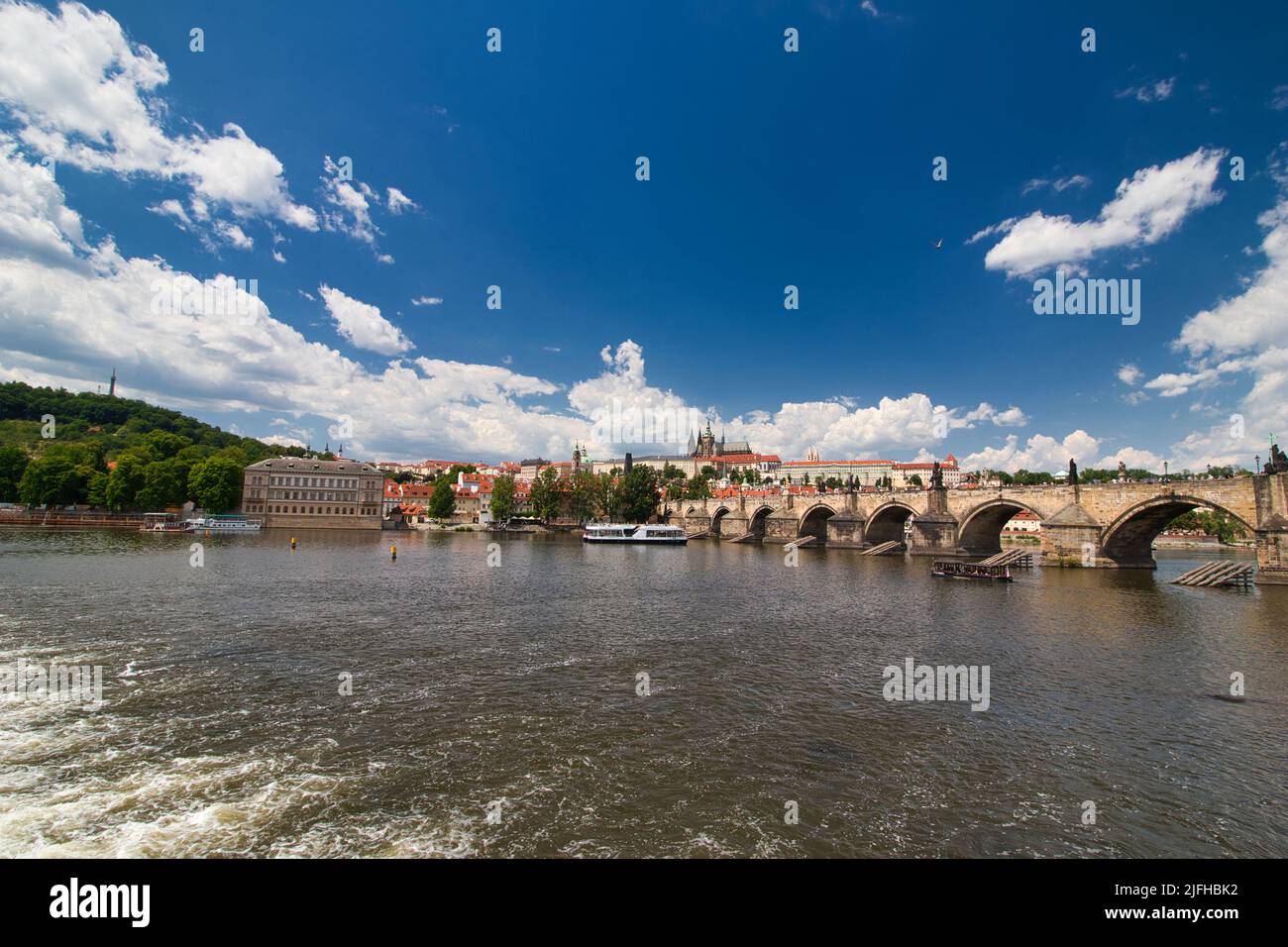 Vue sur la Vltava jusqu'au pont Charles, château de Prague en arrière-plan sous le ciel bleu avec des nuages blancs. Banque D'Images Vue sur la Vltava jusqu'au pont Charles, château de Prague en arrière-plan sous le ciel bleu avec des nuages blancs. Banque D'Images