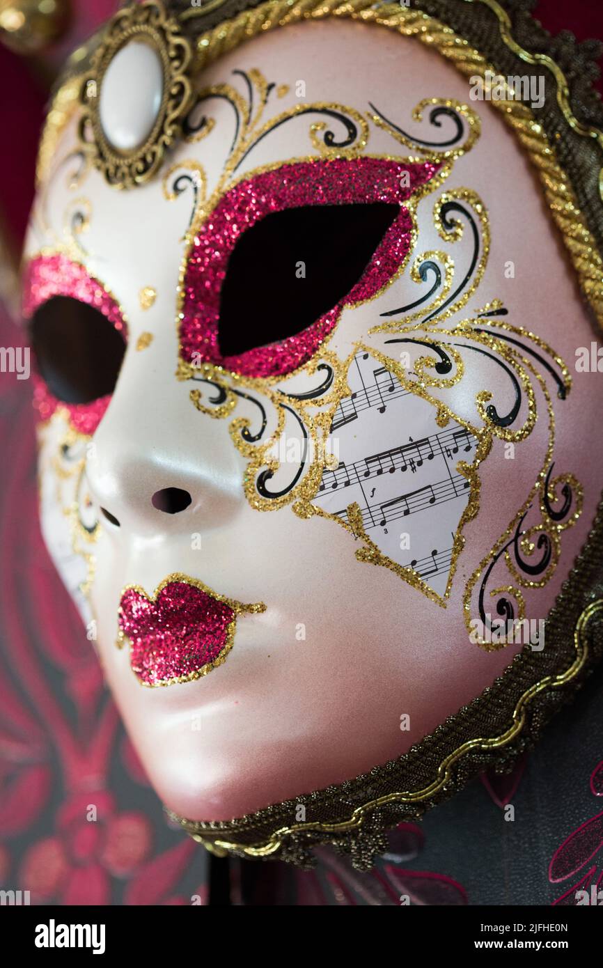Un masque vénitien rouge et or est suspendu à un papier peint décoratif Banque D'Images