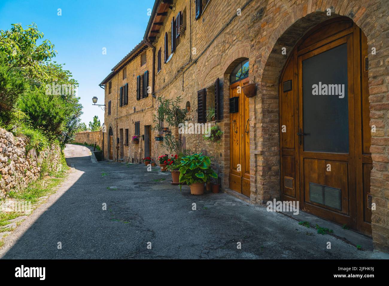 Maisons en briques toscanes rustiques et entrées confortables décorées de fleurs colorées. Vue fantastique sur la rue à San Gimignano, Toscane, Italie, Europe Banque D'Images