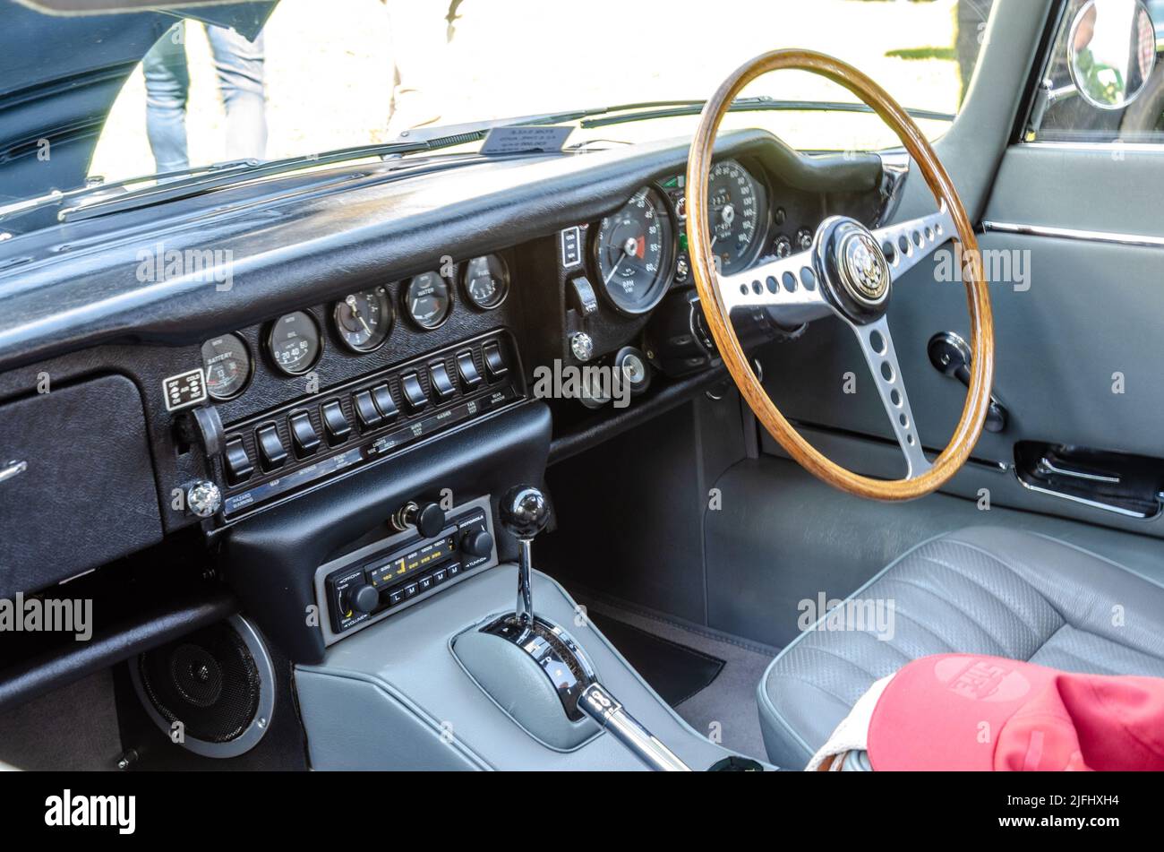 Vue du tableau de bord intérieur d'une voiture Jaguar E-Type classique avec volant en bois et lignes de commutateurs et de jauges. Banque D'Images