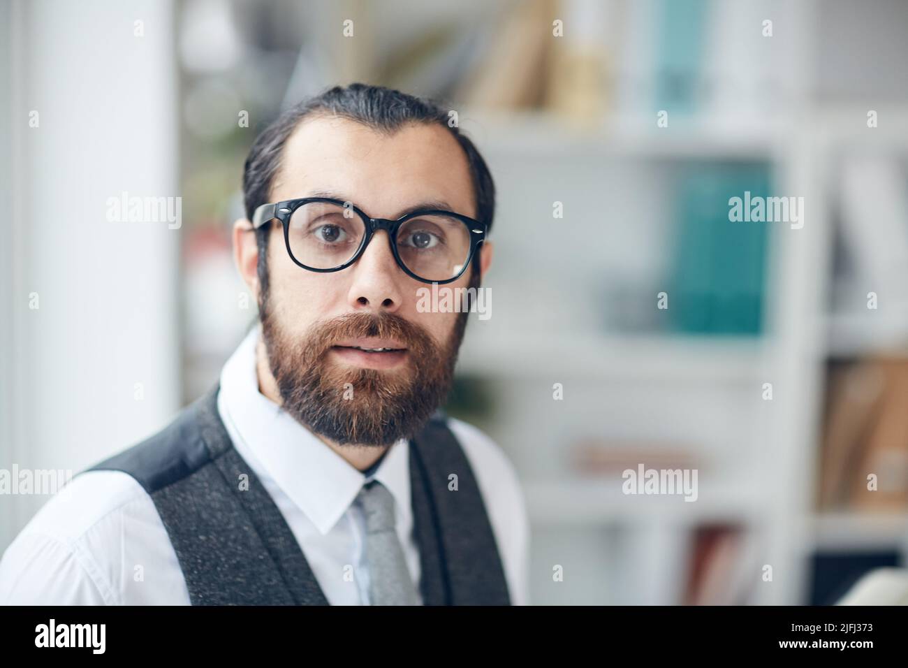 Portrait d'un jeune entrepreneur barbu intelligent et effrayé en lunettes travaillant au bureau Banque D'Images