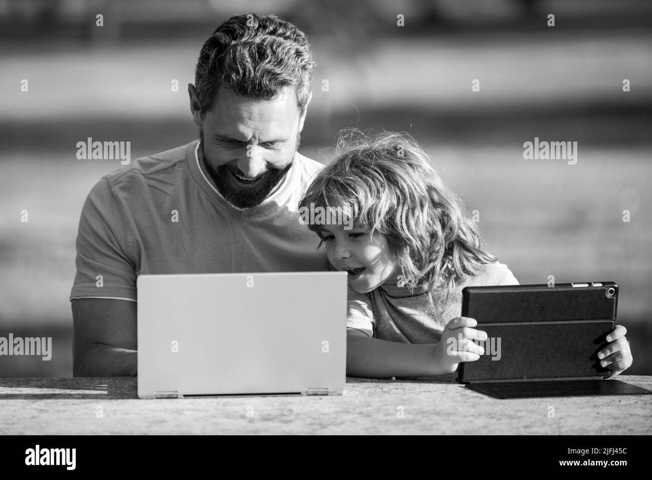 Joyeux père utilisant un ordinateur portable détendez-vous avec un fils écolier tenant un ordinateur portable amusez-vous ensemble, un père souriant et un petit garçon enfant profiter d'un week-end avec des gadgets hors-jeu Banque D'Images