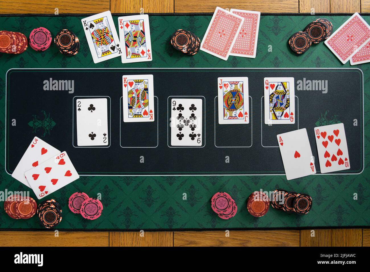 Regarder vers le bas sur une main de chasse royale droite gagnante sur un Texas Hold 'em de poker tapis de jeu avec des piles de jetons de jeu, des cartes de jeu et des mains pliées Banque D'Images