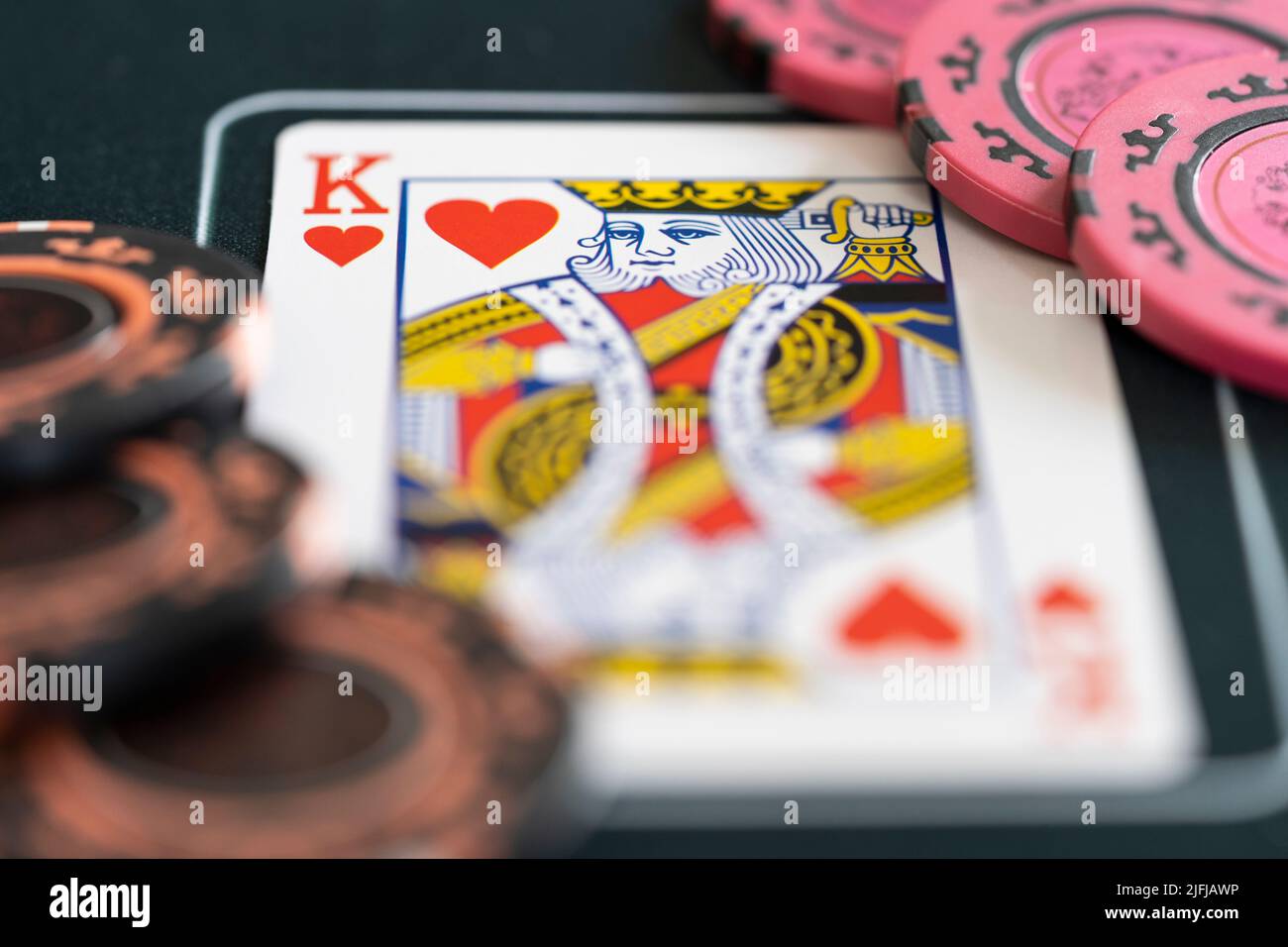 Gros plan d'un roi de coeur jouant carte et jetons de pari de poker sur un tapis de poker. Concept - stratégie de poker, jeu, Paris, dépendance de jeu Banque D'Images