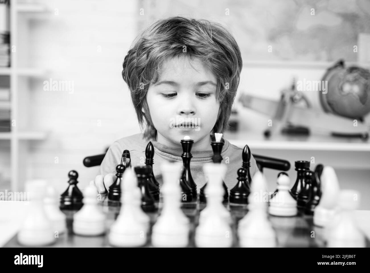 Enfant élève pensant à sa prochaine étape dans une partie d'échecs. Développement précoce des enfants Banque D'Images