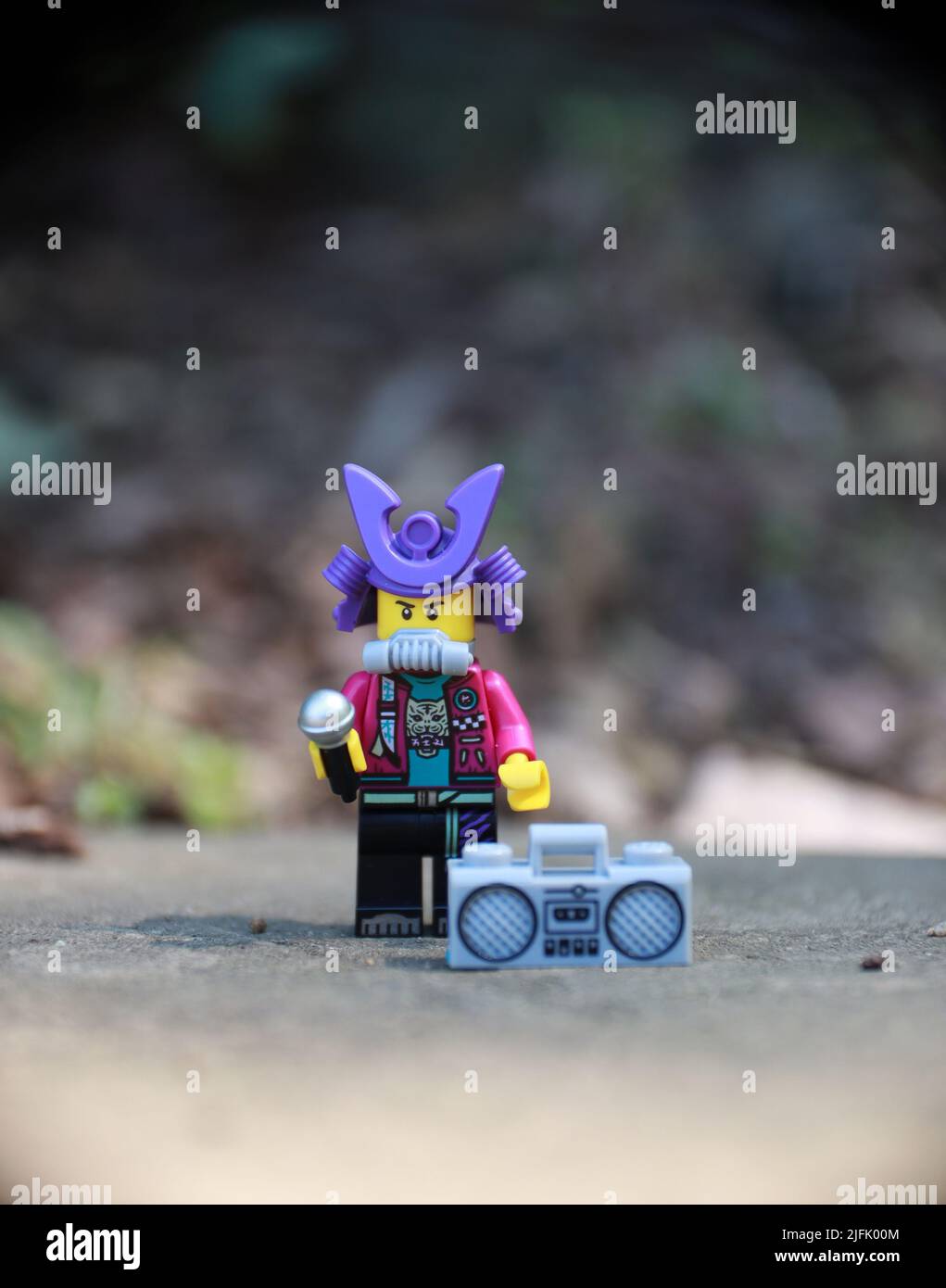 Homme, chapeau violet, figurine jouet, humoristique. Personnage de dessin animé tenant un microphone, chantant avec la musique d'un boom Box. Banque D'Images