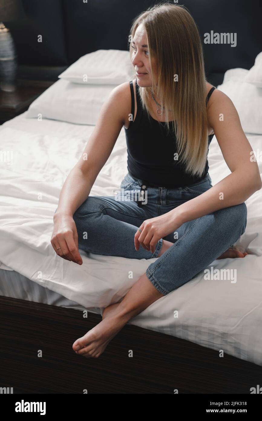 Jeune femme détendue dans la chambre d'hôtel lit planification jour, femme ayant le repos dans l'hôtel moderne pendant le voyage. Personne assise sur le lit. Copier l'espace Banque D'Images