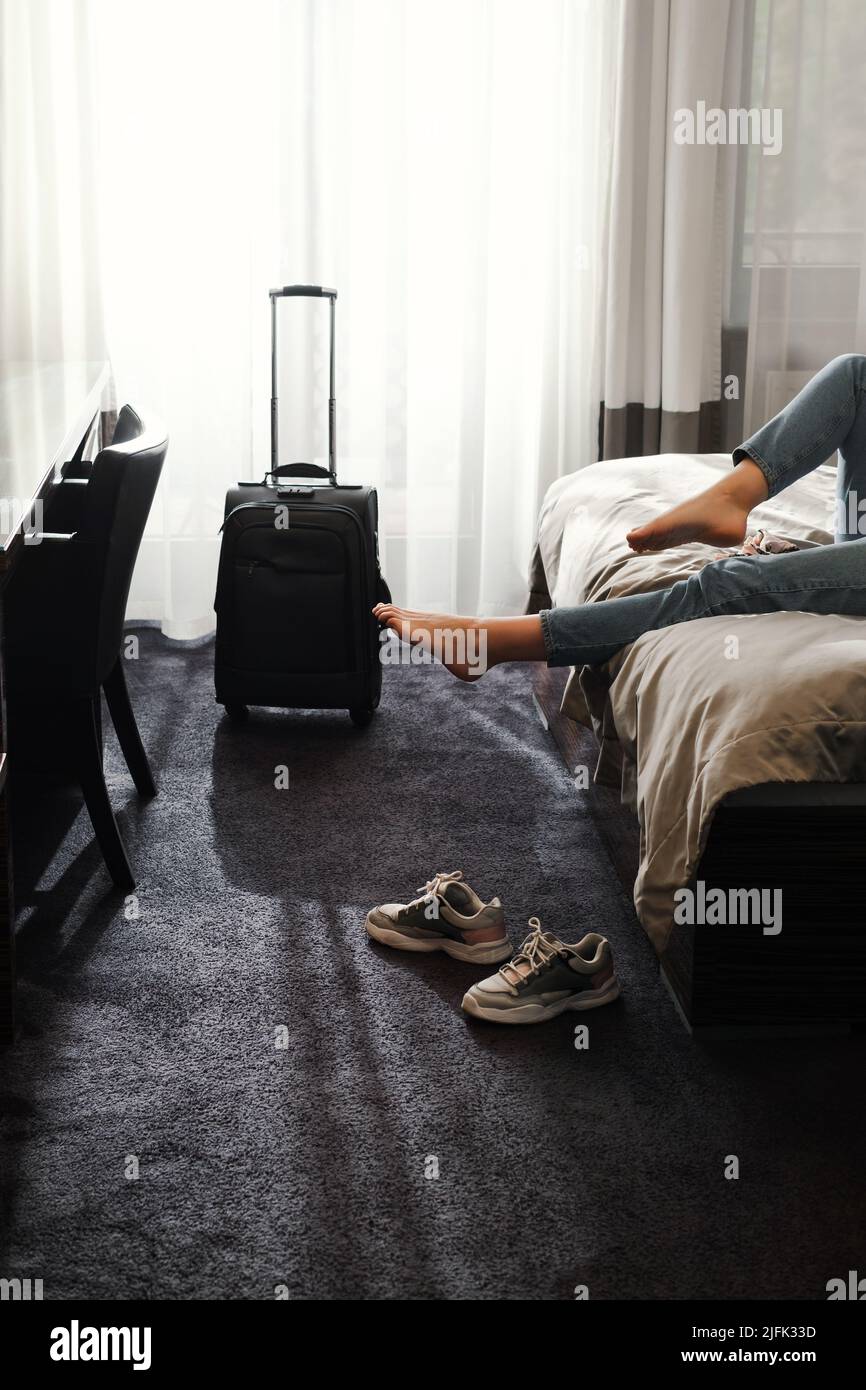 femme prenant des chaussures dans une chambre d'hôtel sur le lit. Touriste se détendre dans la chambre d'hôtel après avoir voyagé avec une valise. Femme ayant le repos après longtemps Banque D'Images