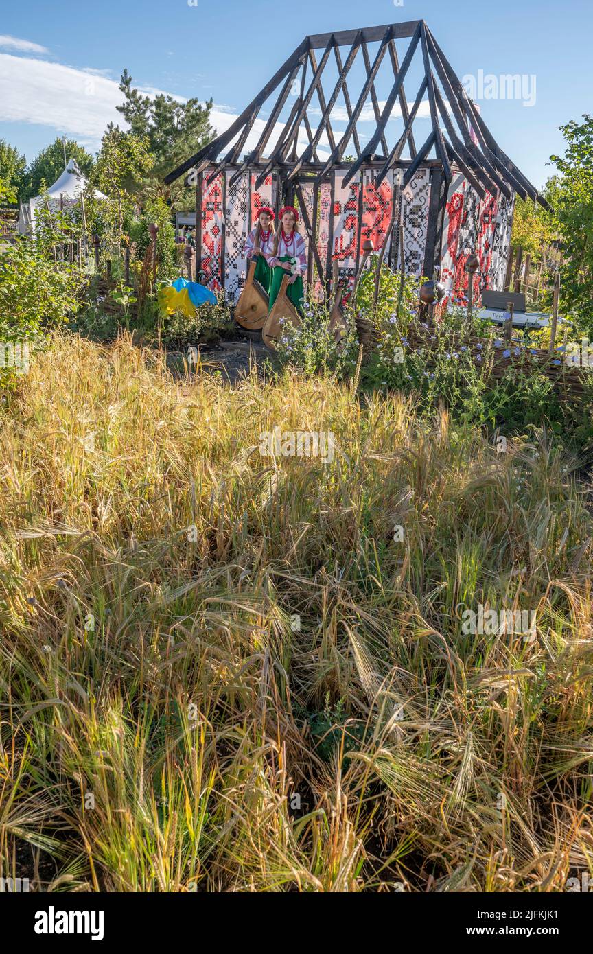 Hampton court Palace, Surrey, Royaume-Uni. 4 juillet 2022. RHS Hampton court Palace Garden Festival Journée de presse pour le plus grand spectacle de fleurs du monde, en cours jusqu'au 9 juillet 2022. Image: Global impact Garden: Bande ukrainienne traditionnelle se produire derrière les champs de blé sur le jardin ce qui ne brûlent pas conçu par Victoria Manoylo et Carrie Preston, une distillation du paysage et de la culture ukrainiennes. Il présente le rushnyk, un tissu brodé utilisé dans de nombreux rituels, comme un symbole de vie et d'identité. Comme une nouvelle peau, les rushnyks ornent les restes d'un chalet brûlé debout comme une silhouette dans le paysage. Crédit: Ma Banque D'Images