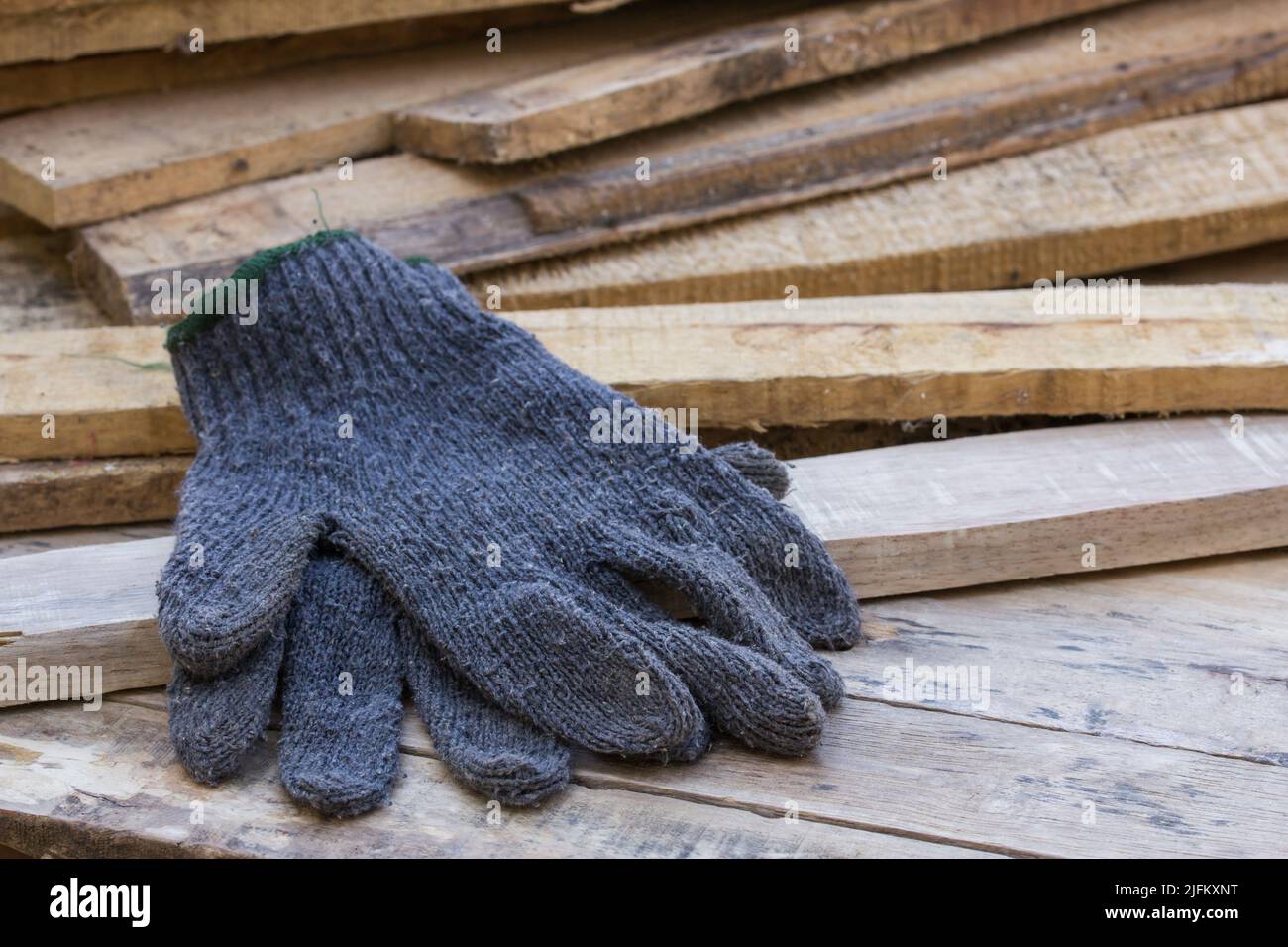 Gants sur table en bois avec une pile de bois derrière Banque D'Images