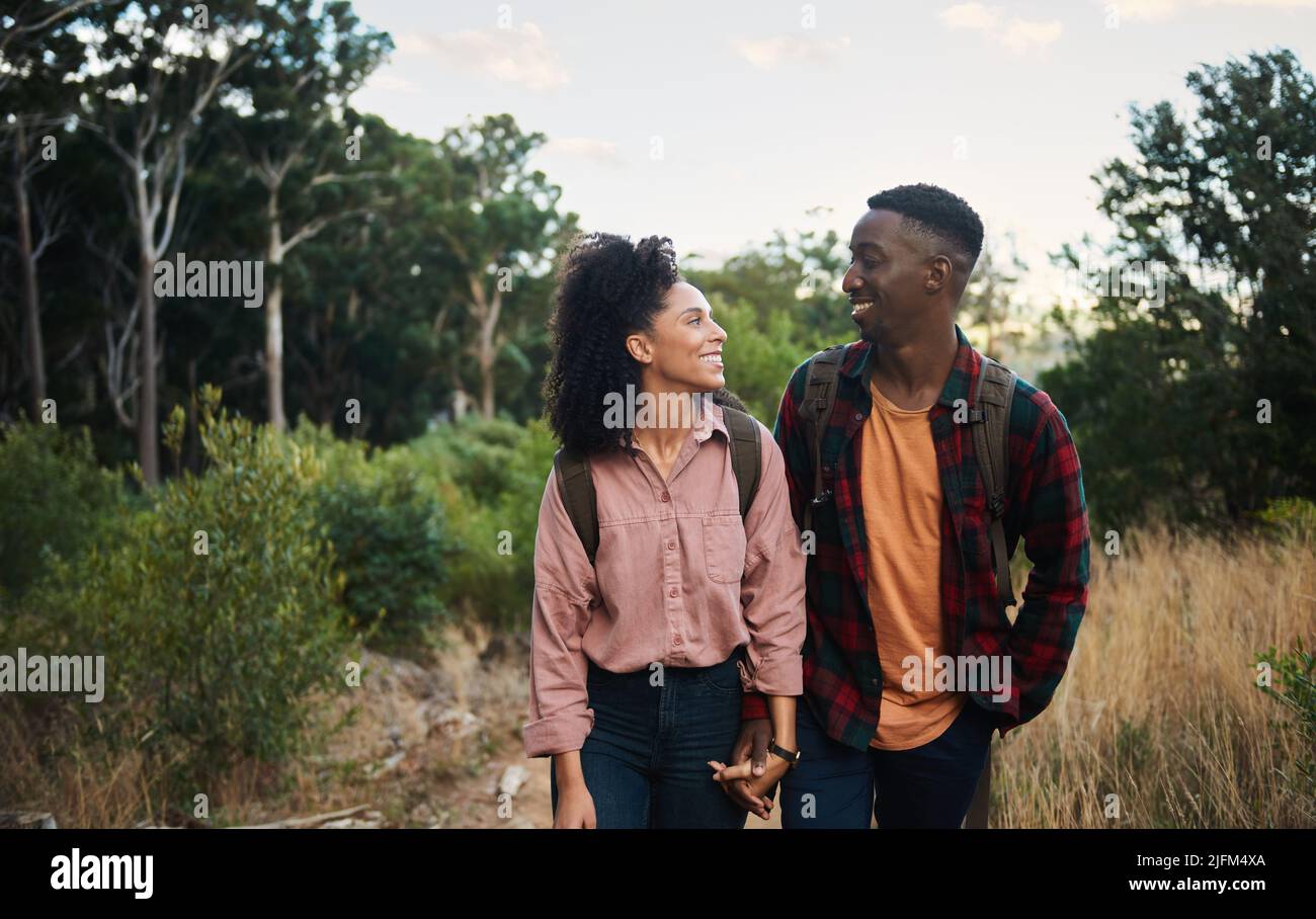 Un jeune couple multiethnique souriant se tenant ensemble pendant une randonnée sur les sentiers Banque D'Images