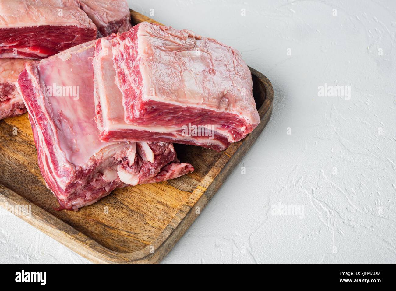 Côtes de bœuf marbré Angus noir brut, sur fond de pierre blanche, avec espace pour le texte Banque D'Images