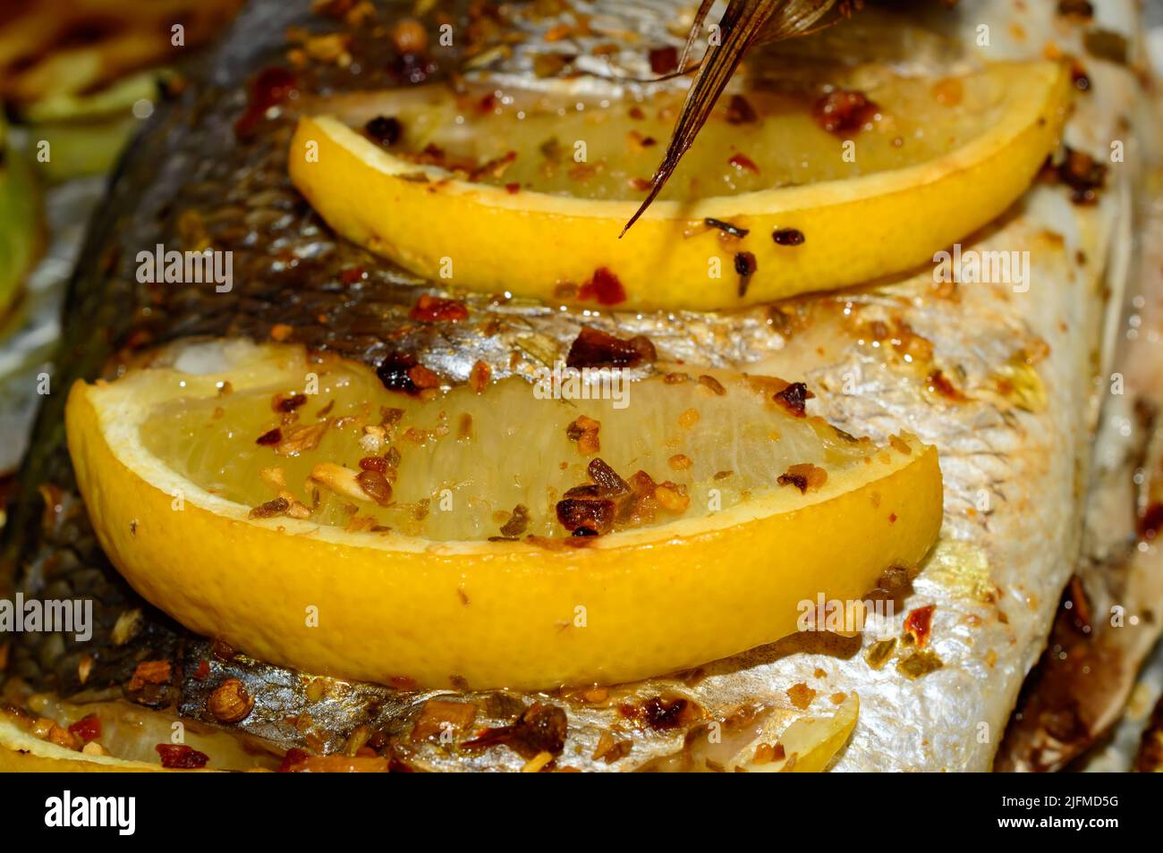 Macro photo d'un citron avec des épices sur le dessus du poisson dorado. Poisson espar doré recouvert de citrons. Banque D'Images