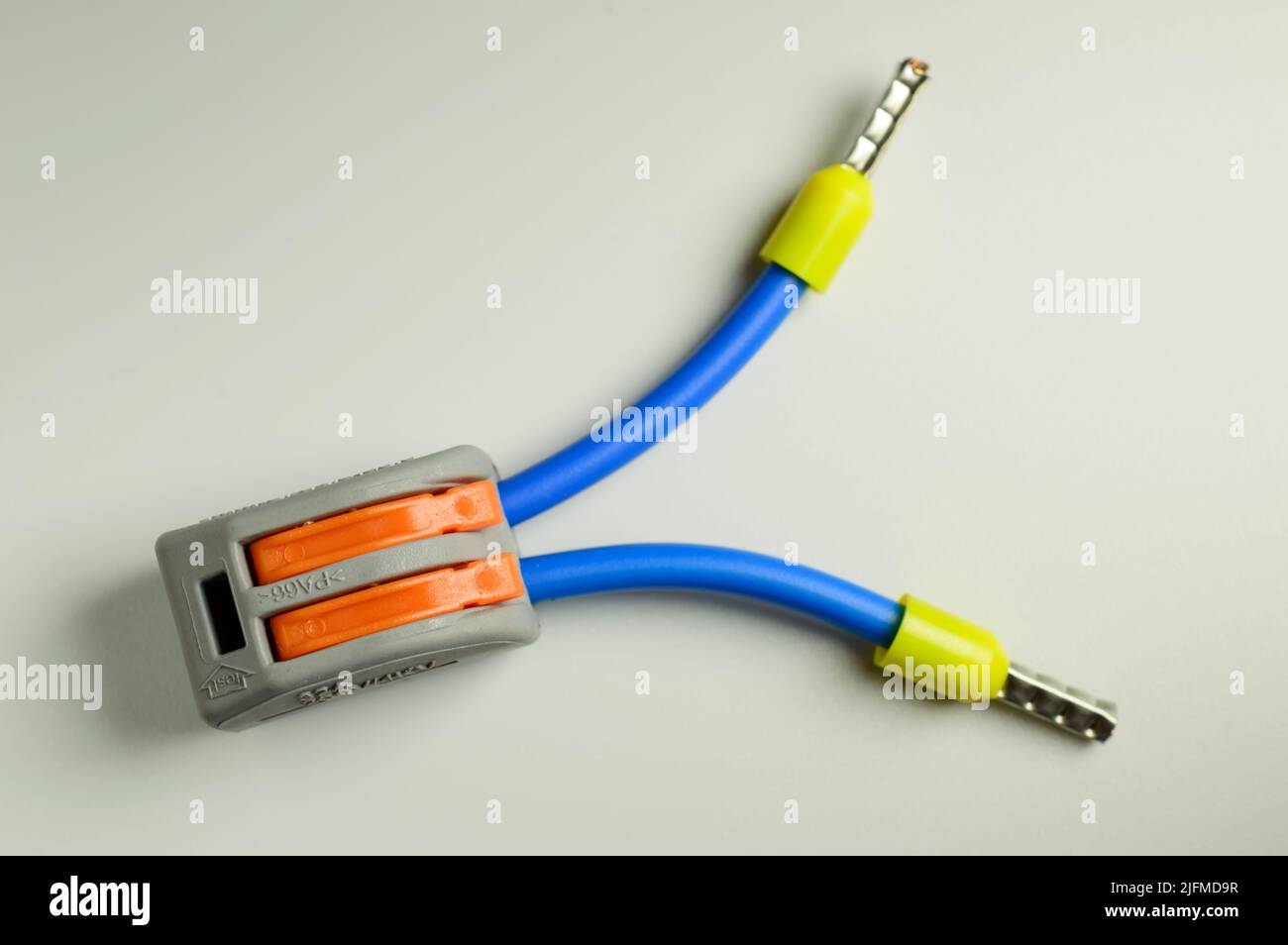 Borne électrique pour connexion rapide de fils avec fils bleus connectés avec des embouts jaunes - macro photo. Image d'arrière-plan. Mise au point sélective. Banque D'Images