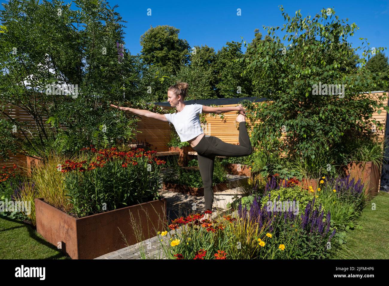 Londres, Royaume-Uni. 4 juillet 2022. Hannah Stevenson, instructeur de Pliates, effectue une routine de yoga dans le Lunch Break Garden, un jardin de mise en route, conçu par Inspired Earth Design, lors de la prévisualisation de la presse au RHS Hampton court Palace Garden Festival. Le plus grand spectacle floral au monde comprend des jardins de designers inspirants, des conférences de célébrités, des démonstrations et des ateliers. Credit: Stephen Chung / Alamy Live News Banque D'Images