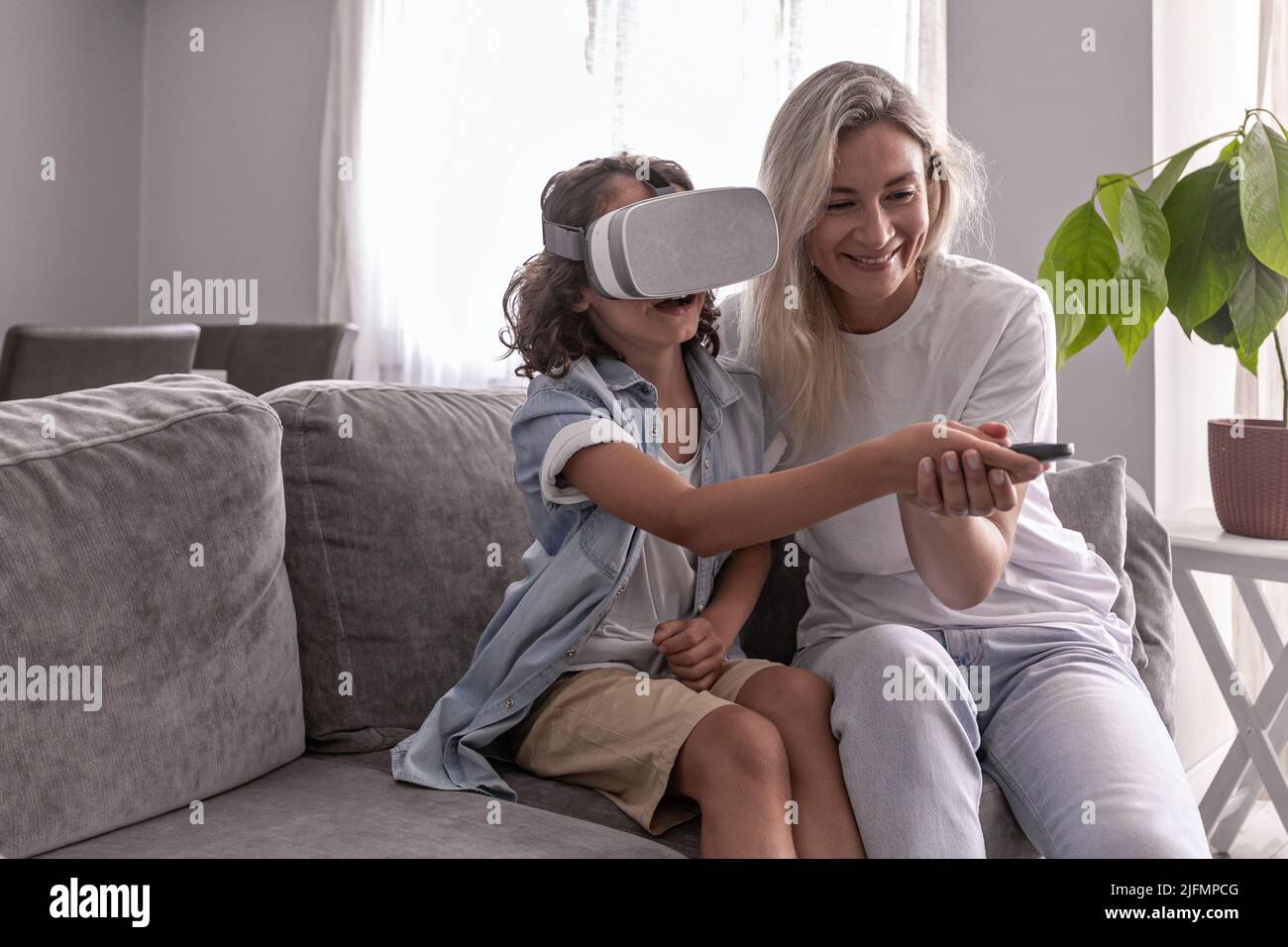 garçon enfant portant un casque de réalité virtuelle avec sa mère des lunettes vr dans le salon à la maison pour s'amuser Banque D'Images