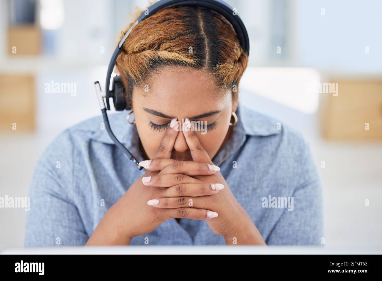 Jeune femme de race mixte stressée agent de centre d'appels se faisant mal de tête en travaillant au bureau. Conseiller faisant des erreurs et de la difficulté avec Banque D'Images