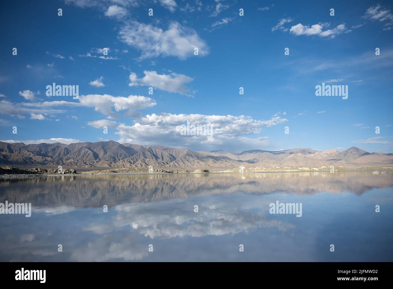 Une côte montagneuse et le ciel avec plusieurs nuages parfaitement reflétés dans un lac Banque D'Images